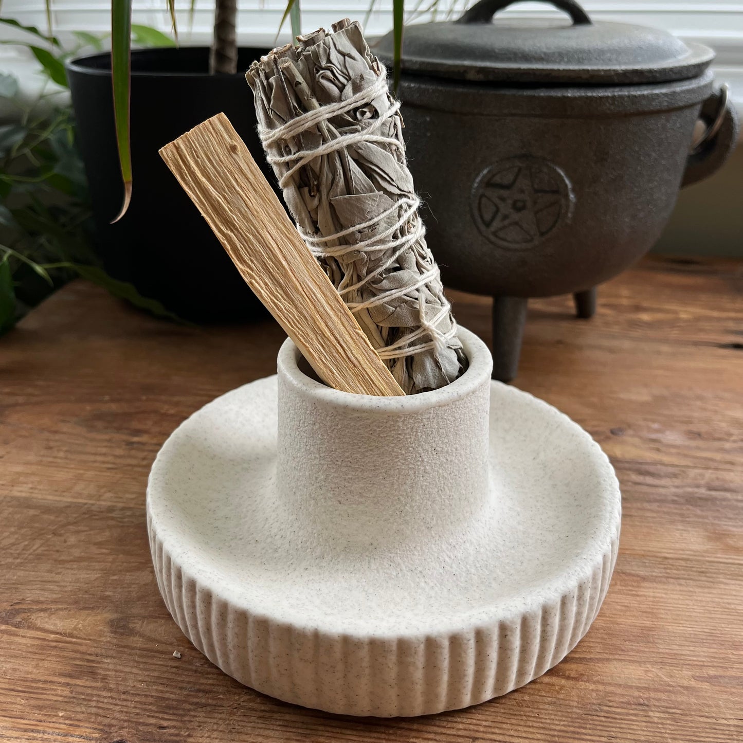 Ceramic holder with smudge sticks on a wooden surface