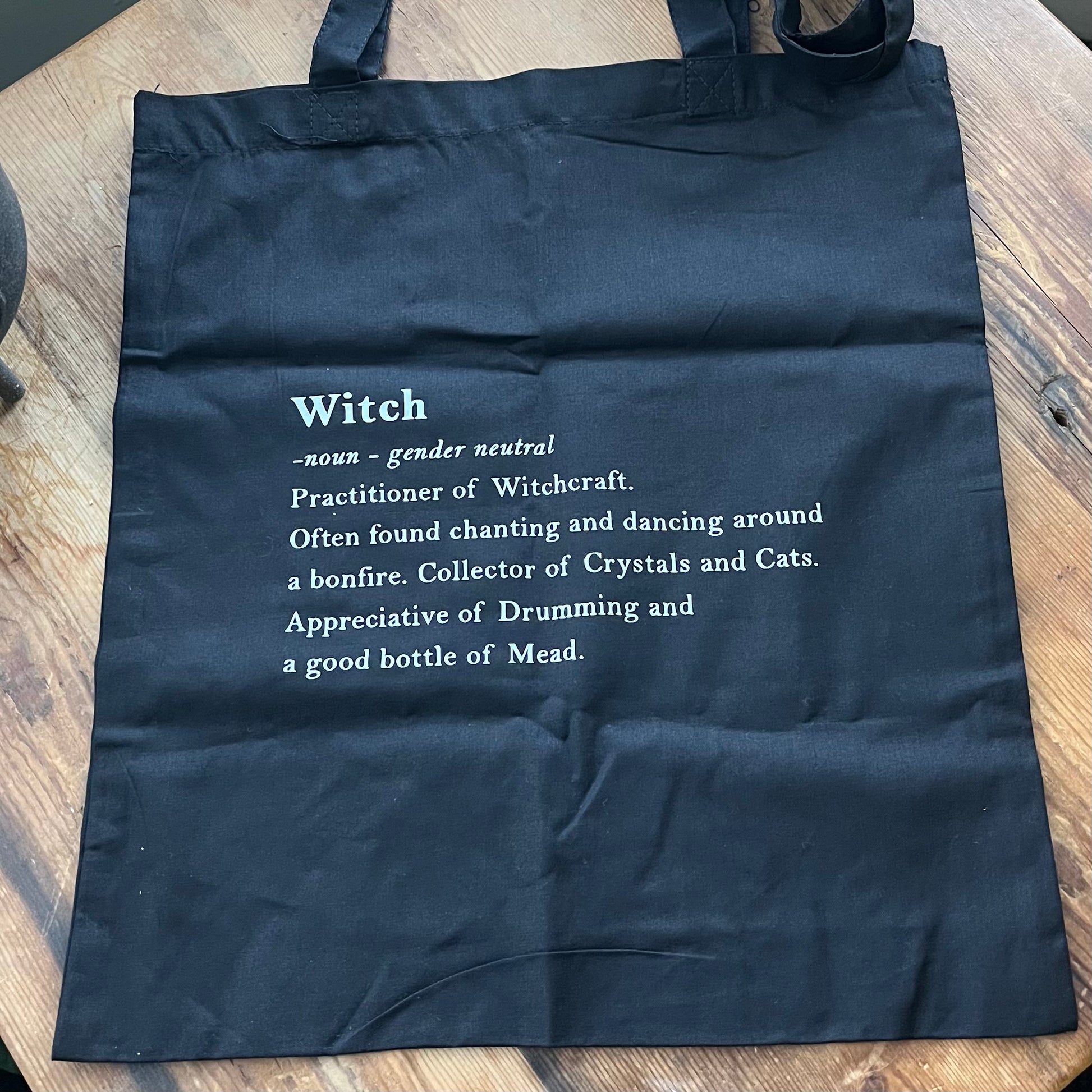 Black tote bag with definition of a witch in white text 