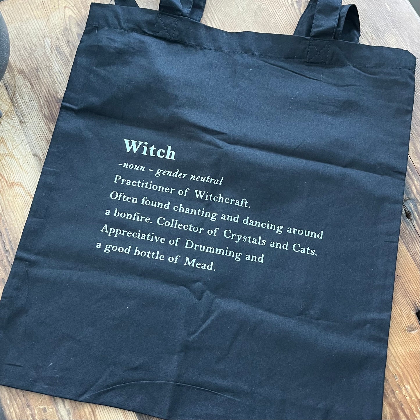 Black tote bag with definition of a witch in white text 