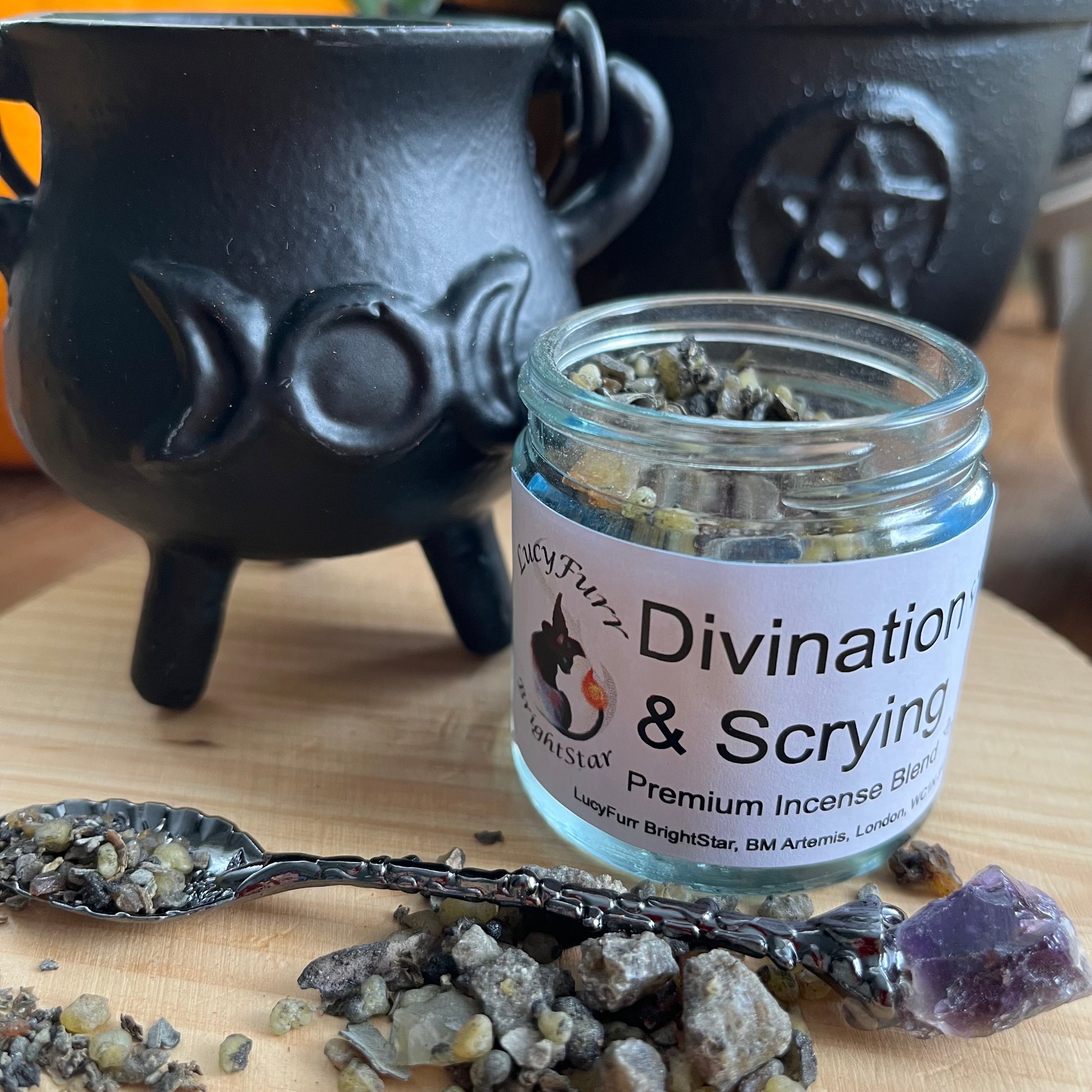 Jar of 'Divination & Scrying' premium incense blend with a black cauldron and spoonful of incense on a wooden surface.