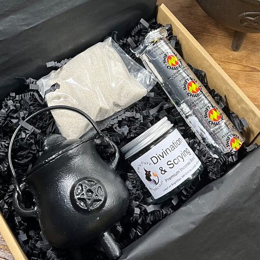 Box containing a black cauldron, jar labeled 'Divination & Scrying', charcoal discs and cauldron sand