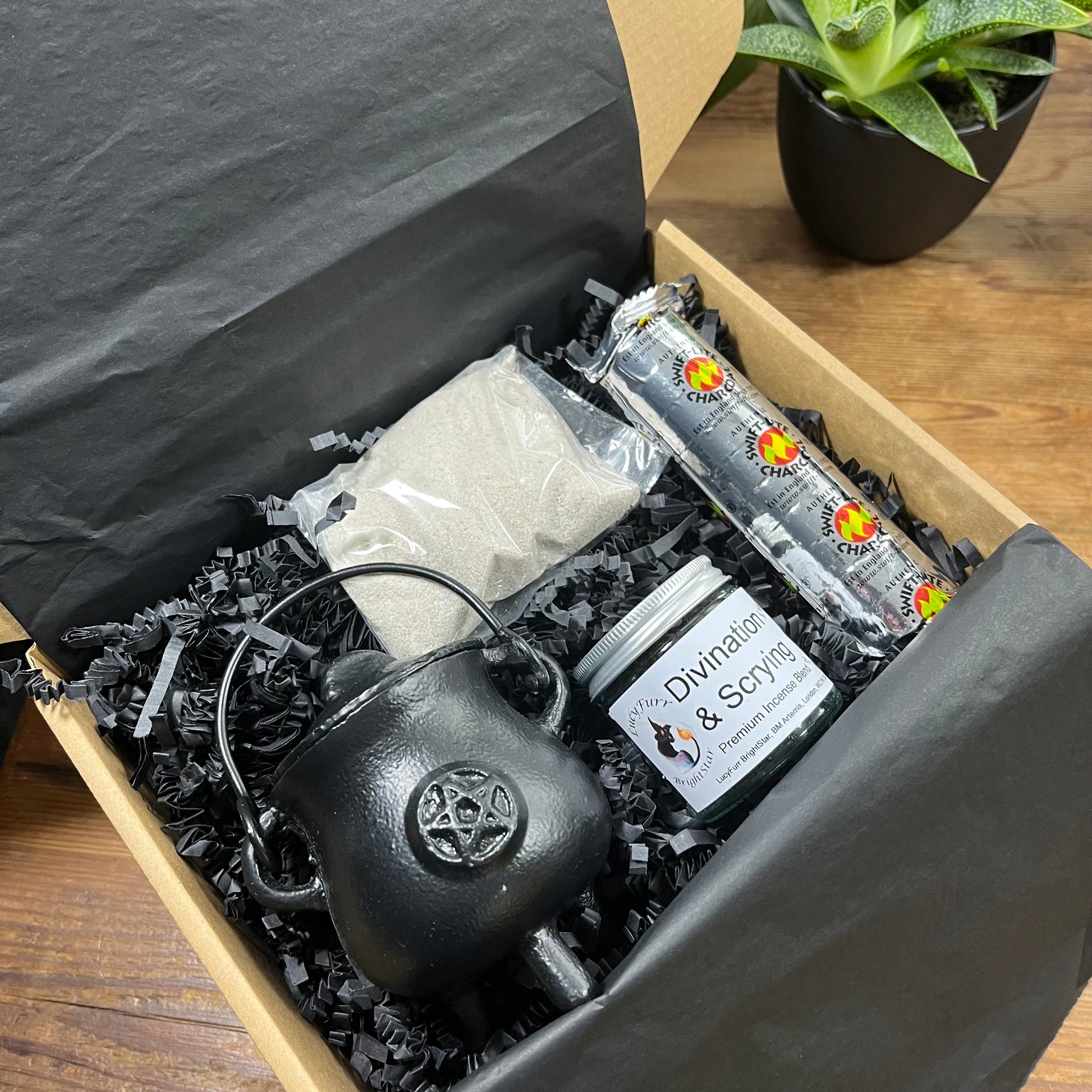 Gift box containing a black cauldron, jar labeled 'Divination & Scrying', charcoal discs and cauldron sand