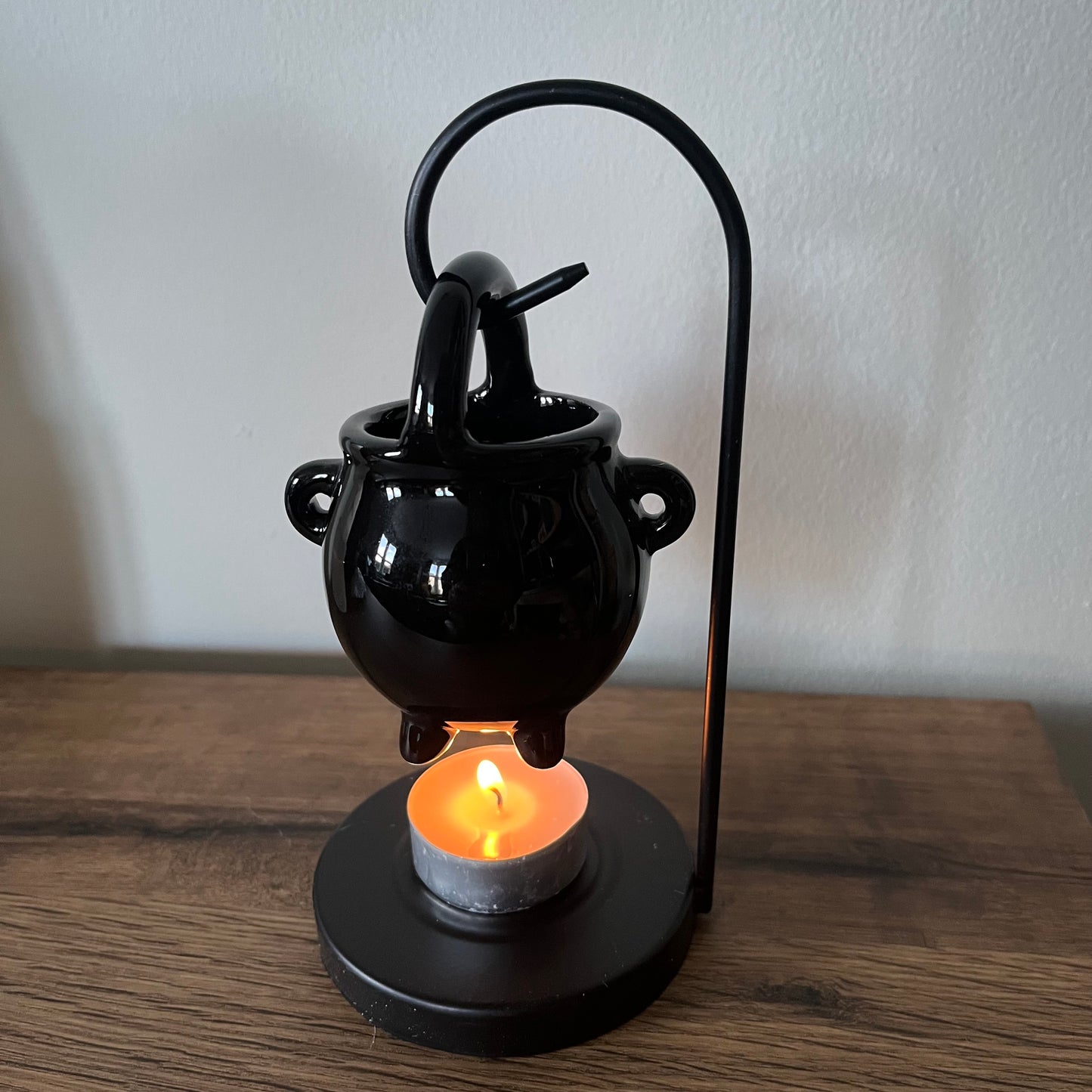 Black ceramic lamp with a candle on a wooden surface