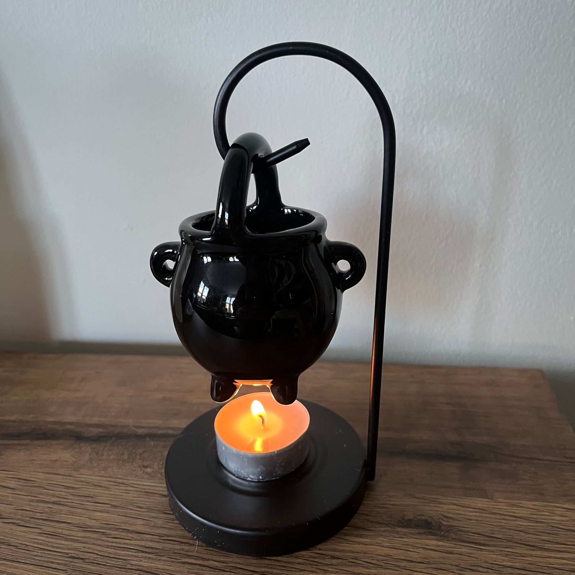 Black ceramic lamp with a candle on a wooden surface