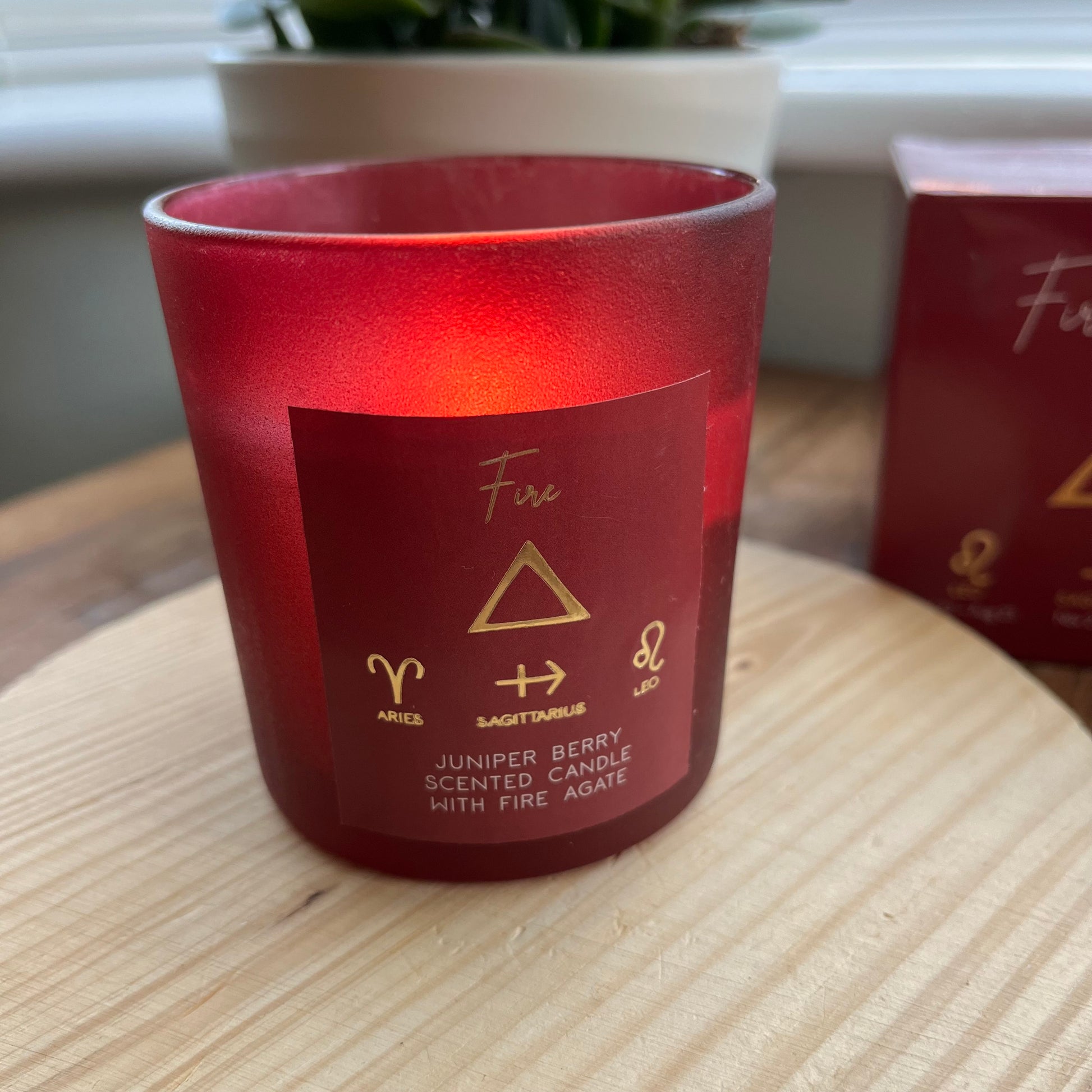 'Fire element candle' A red glassed candle featuring the word fire and the symbol for the element of fire plus the symbols for the firey zodiac signs of Aries, Sagittarius and Leo. 