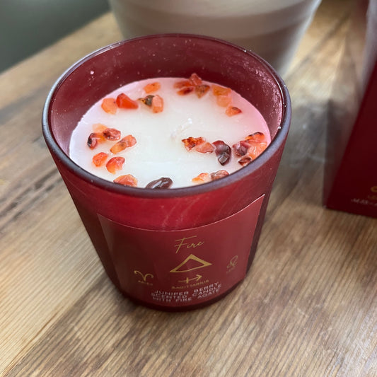 'Fire element candle' A red glass candle holder featuring the word fire and the symbol for the element of fire plus the symbols for the firey zodiac signs of Aries, Sagittarius and Leo. The candle itself is whiite with red agate crystals scattered on top.