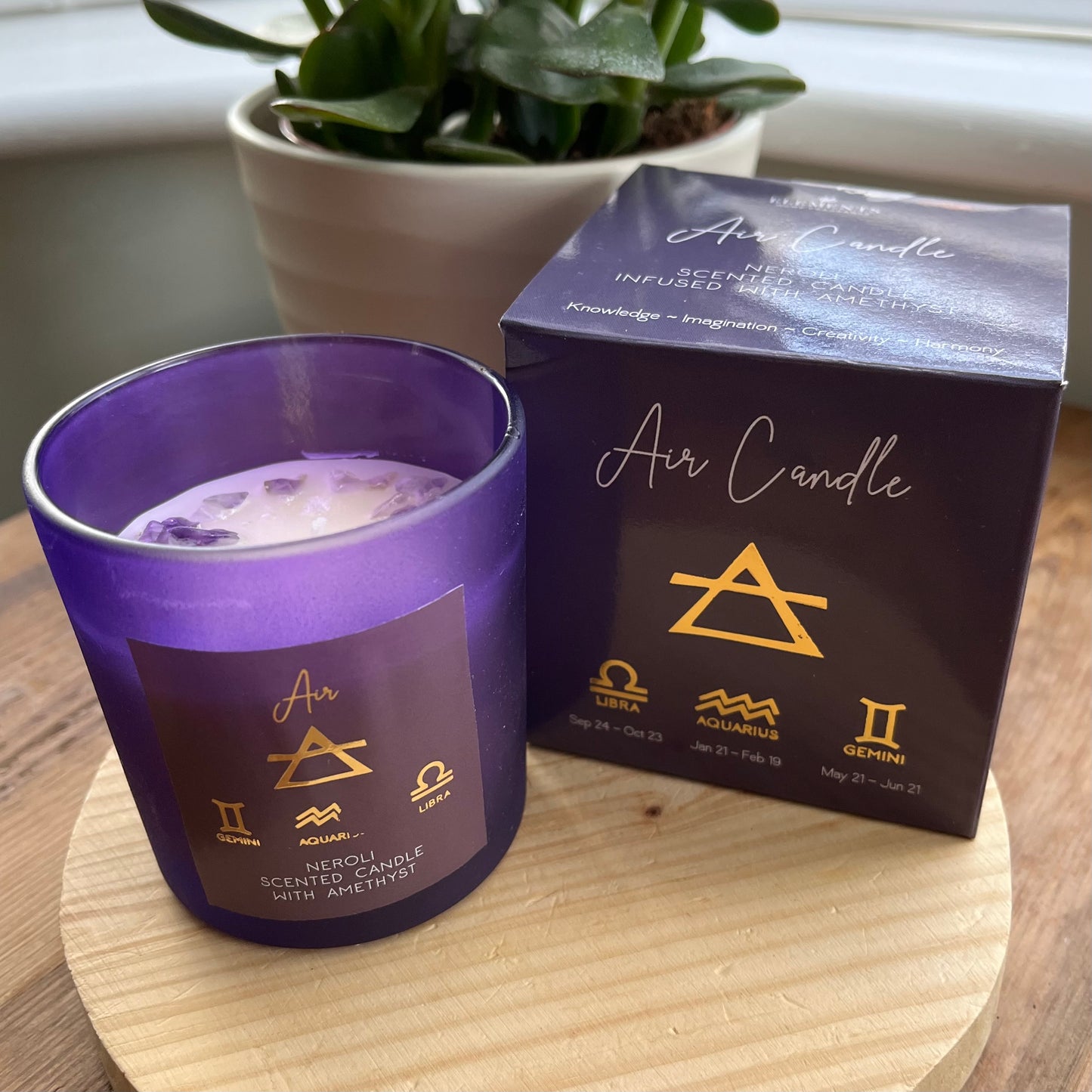 Purple glass lidded candle  with Amethyst gemstone chips featuring the word Air and the air element symbols plus the symbols for the airy zodiac signs Libra, Aquarius and Gemini . Alongside it's presentation box featuring the same words and symbols.