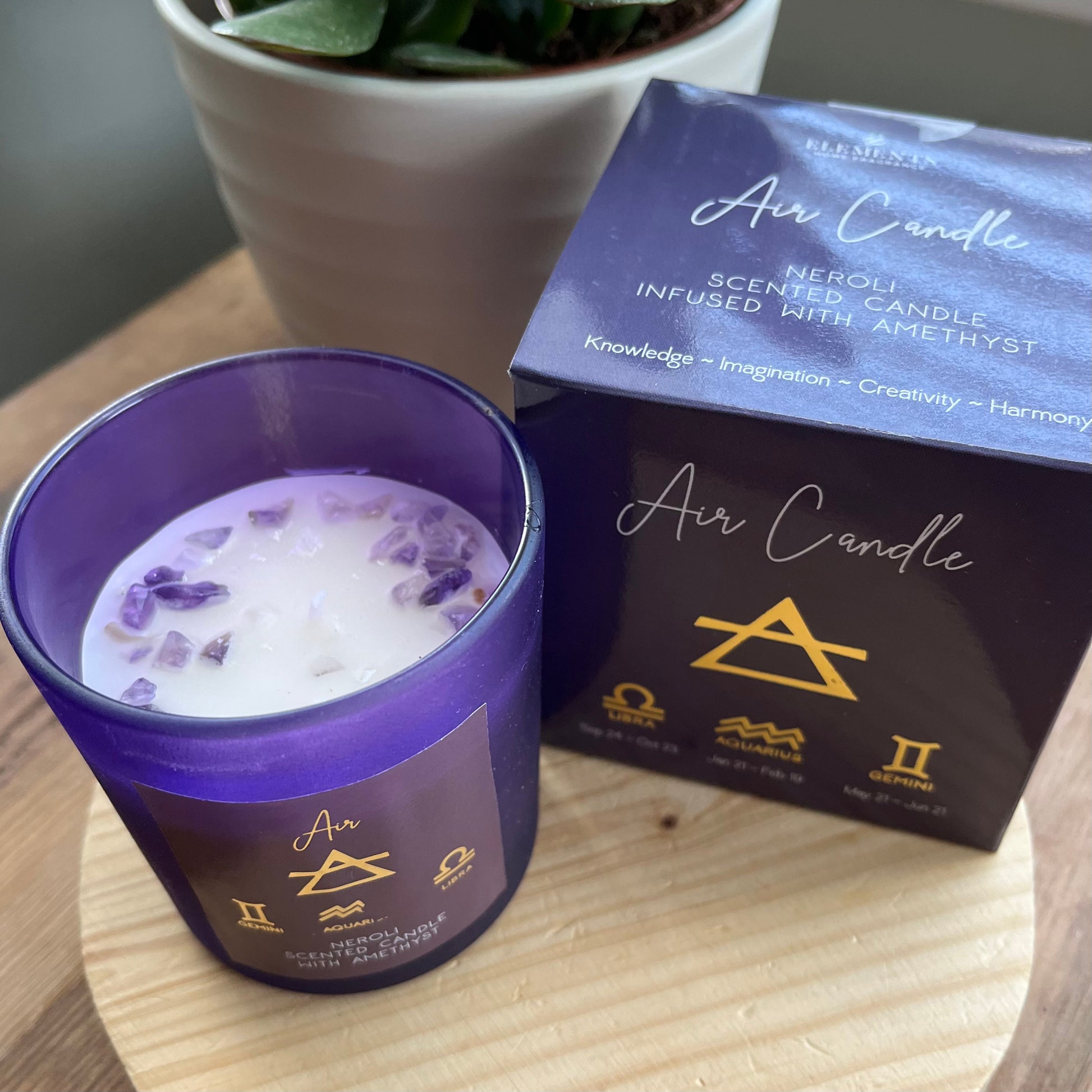 Purple glass lidded candle adorned with beautiful purple Amethyst crystal chips and featuring the word Air and the air element symbols plus the symbols for the airy zodiac signs Libra, Aquarius and Gemini . Alongside it's presentation box featuring the same words and symbols.