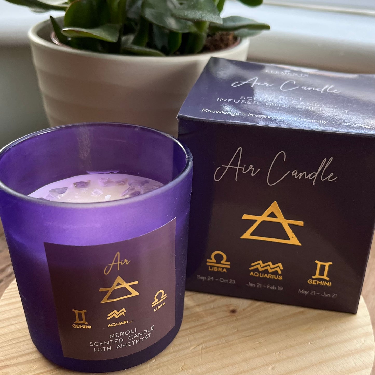 Purple glass lidded candle adorned with beautiful Amethyst crystal chips and featuring the word Air and the air element symbols plus the symbols for the airy zodiac signs Libra, Aquarius and Gemini . Alongside it's presentation box featuring the same words and symbols. 