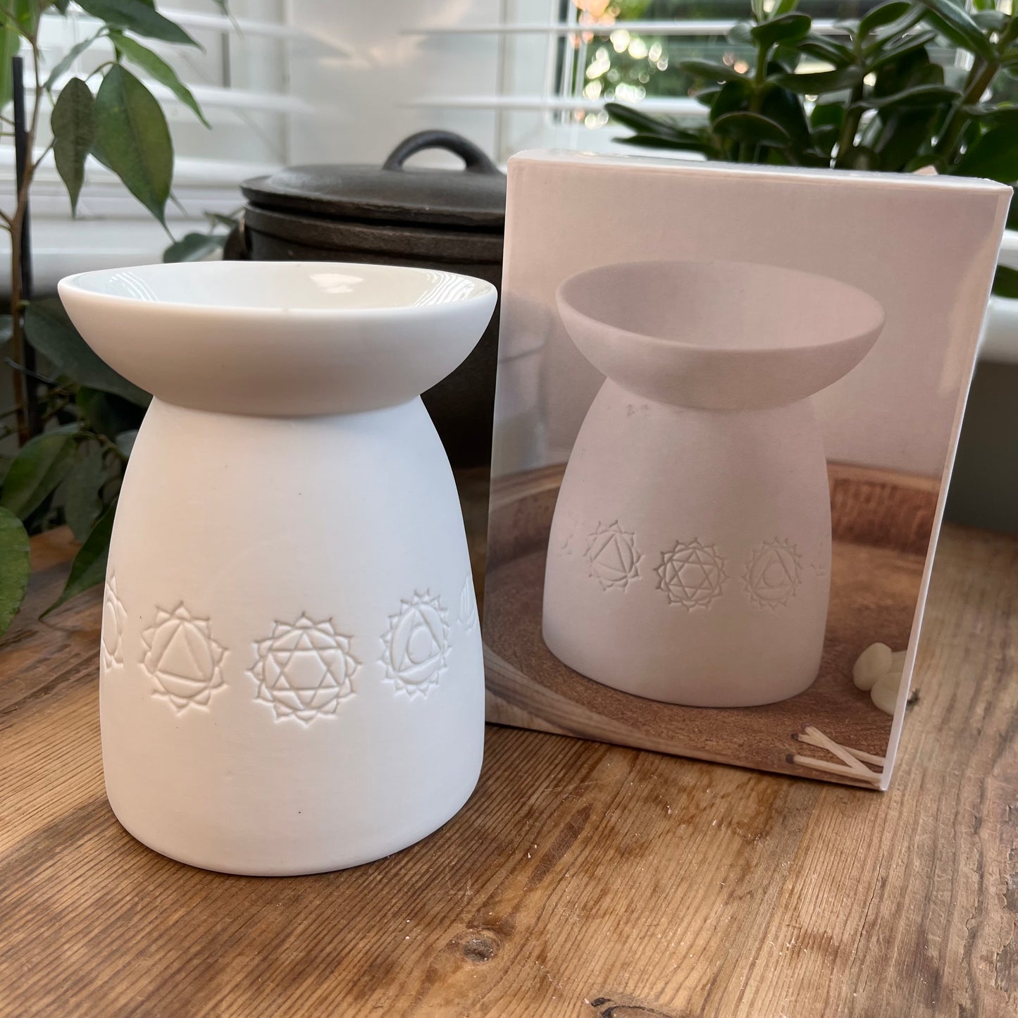 White ceramic oil burner with the symbols of the seven chakras itched around it. 