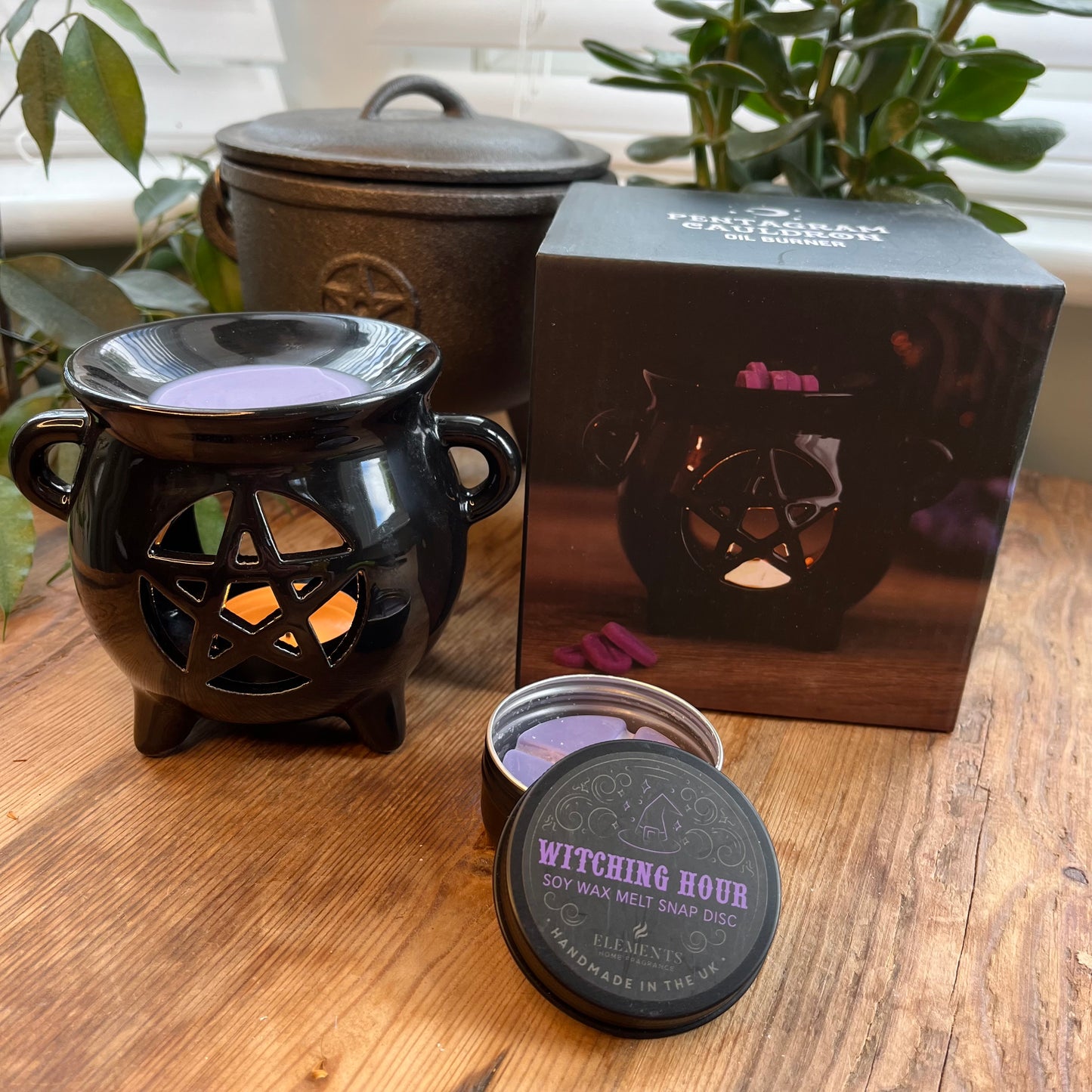 Black shiny ceramic oil burner with pentagram cutout design. Pictured in use with wax melts. 