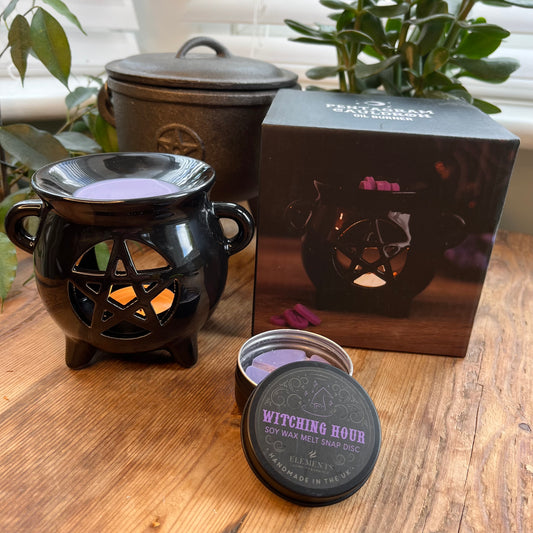 Black shiny ceramic oil burner with pentagram cutout design. Pictured in use with wax melts. 