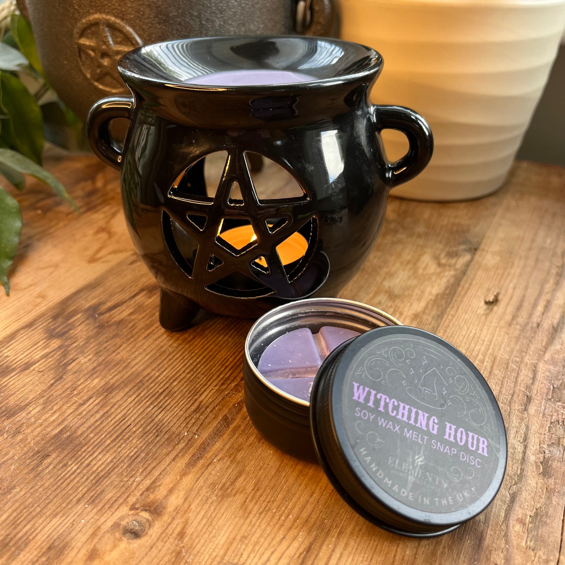 Black shiny ceramic oil burner with pentagram cutout design. Pictured in use with wax melts. 