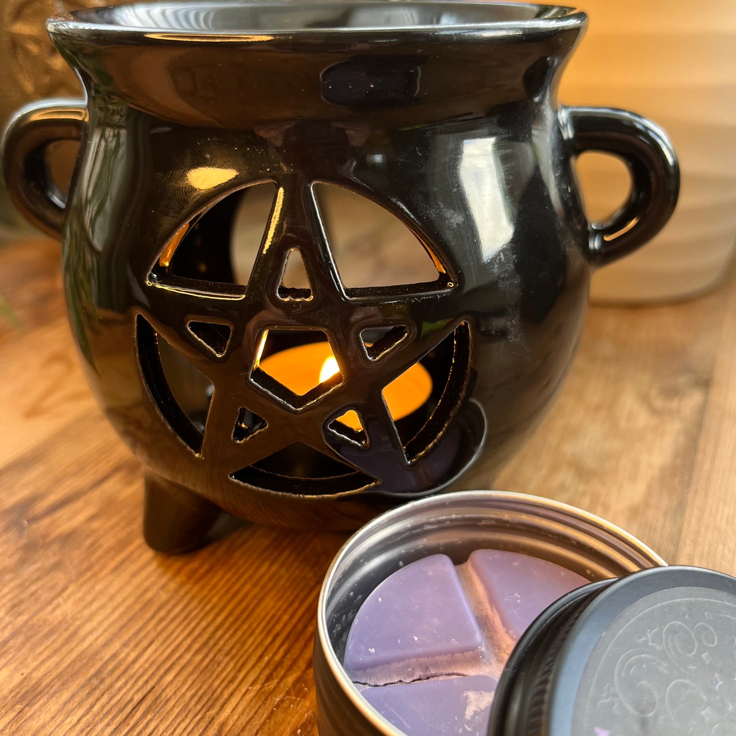 Black shiny ceramic oil burner with pentagram cutout design. Pictured in use with wax melts. 