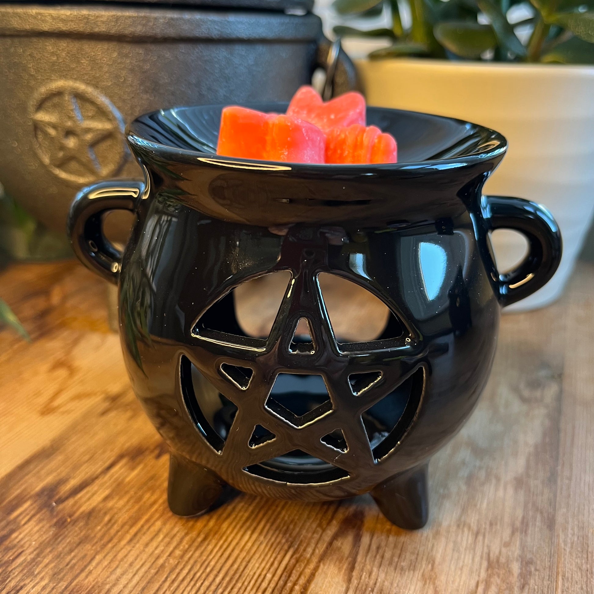 Black shiny ceramic oil burner with pentagram cutout design. Pictured in use with wax melts. 