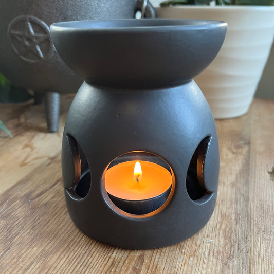 Black ceramic oil burner with a cutout triple moon design and a cool, matt finish.