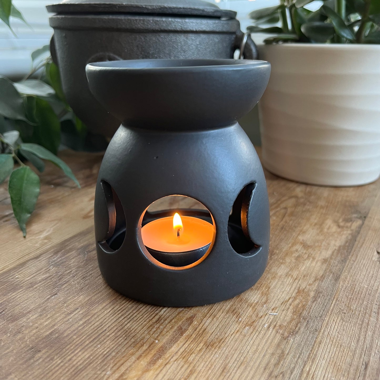 Black ceramic oil burner with a cutout triple moon design and a cool, matt finish.