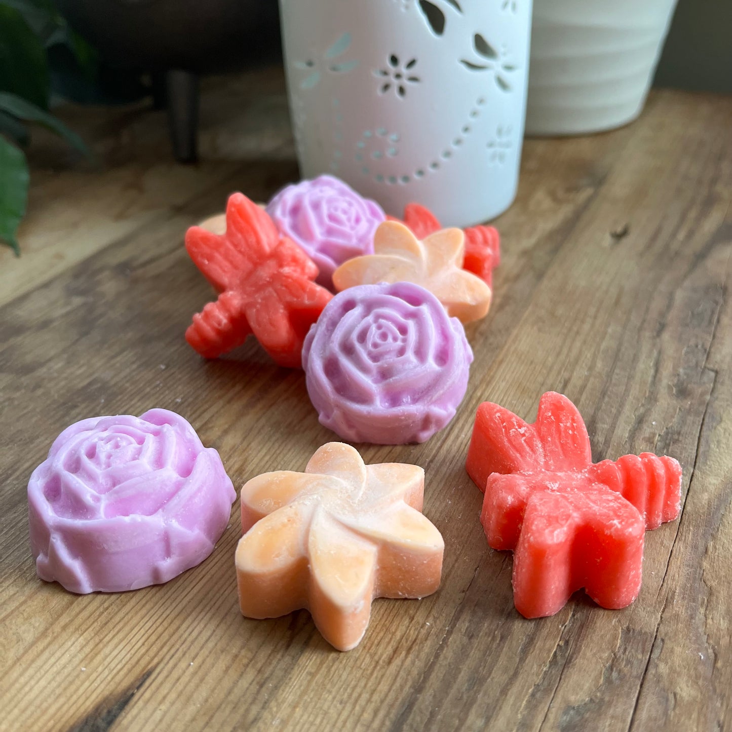 9 wax melts on a table 3 flower shaped, 2 starshaped, 3 dragonfly shaped 