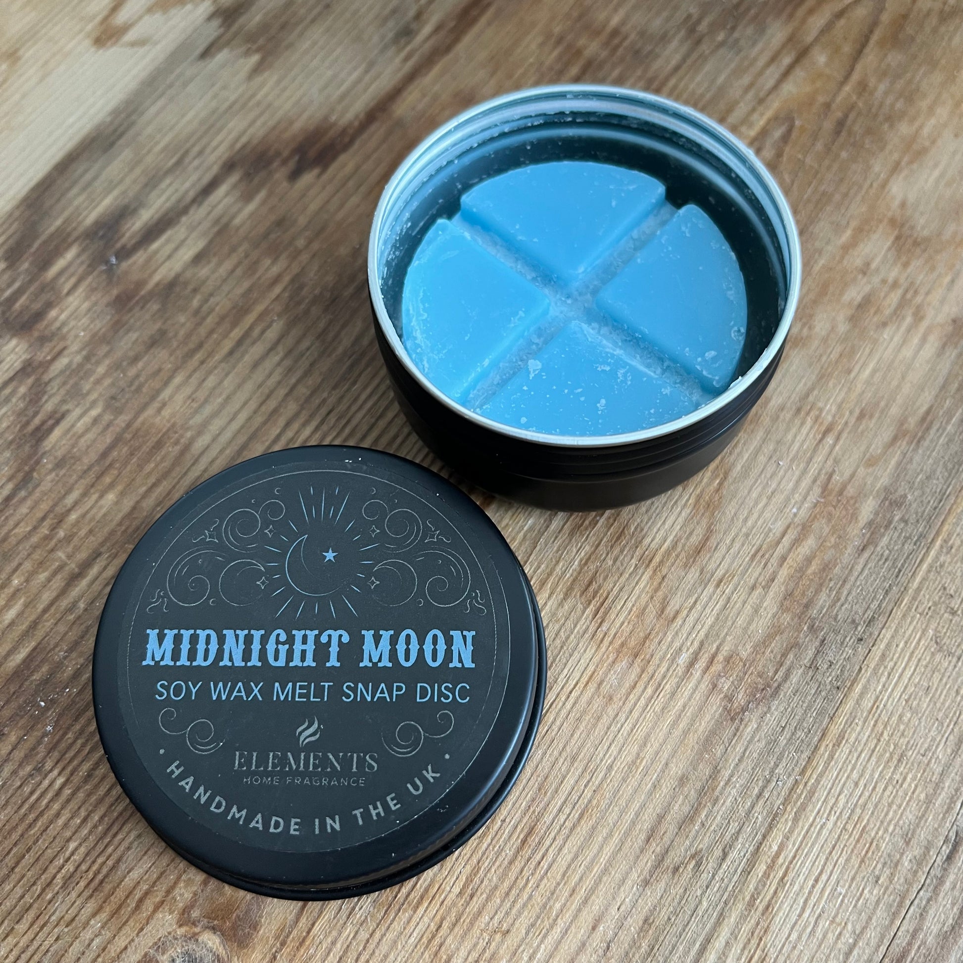 circular tin containing blue soy wax melt divided into 4. The lid of the tin reads midnight moon soy wax melt snap disc 