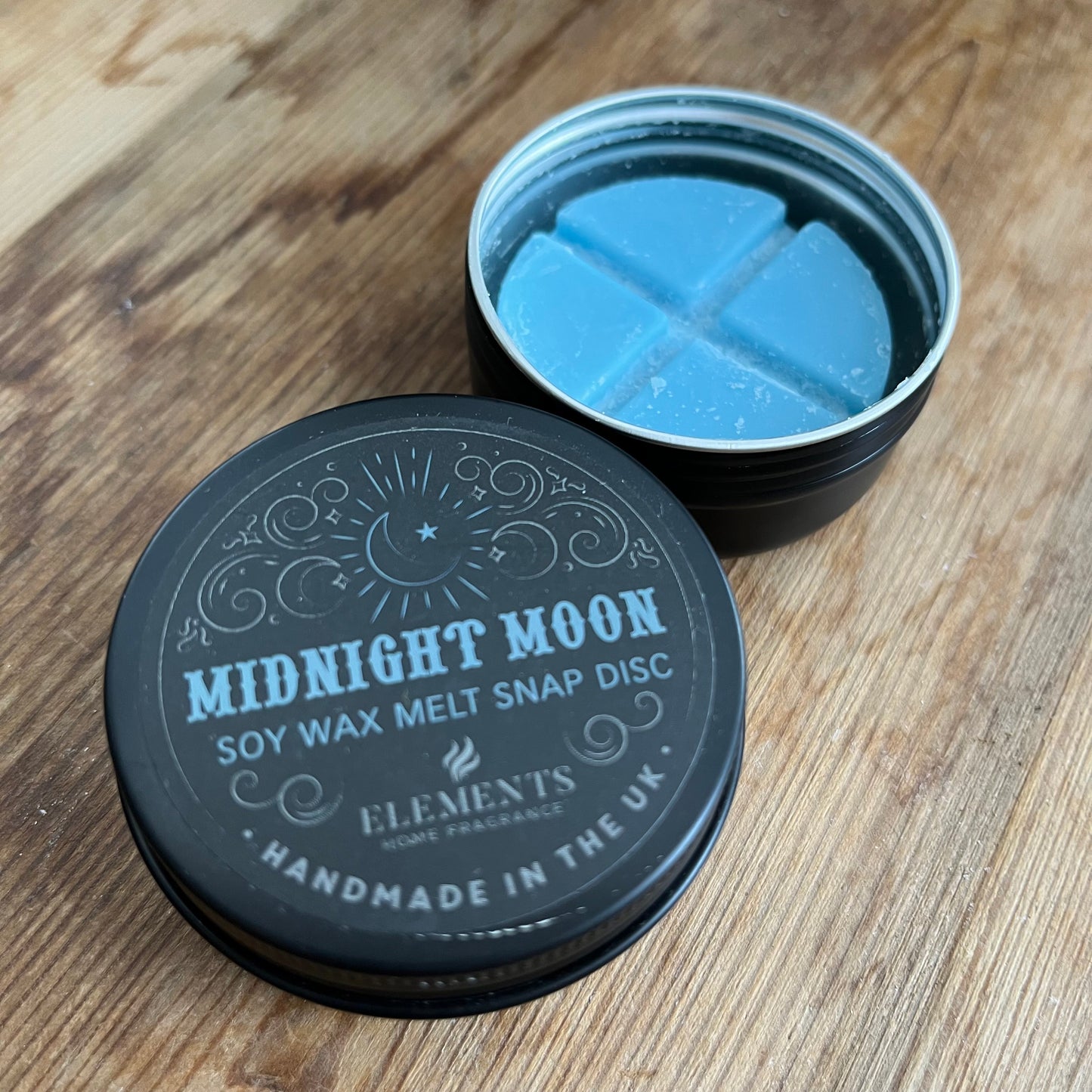 circular tin containing blue soy wax melt divided into 4. The lid of the tin reads midnight moon soy wax melt snap disc 