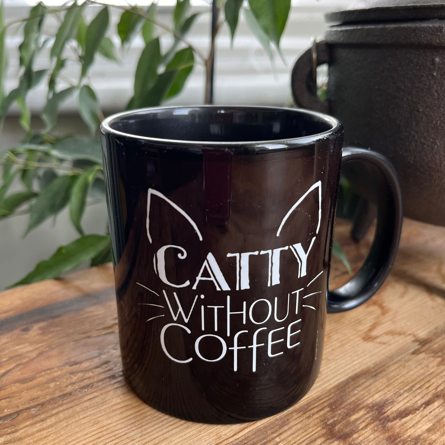 Black mug with the words 'caty without coffee' in white and an illustration of cats ears and whiskers 