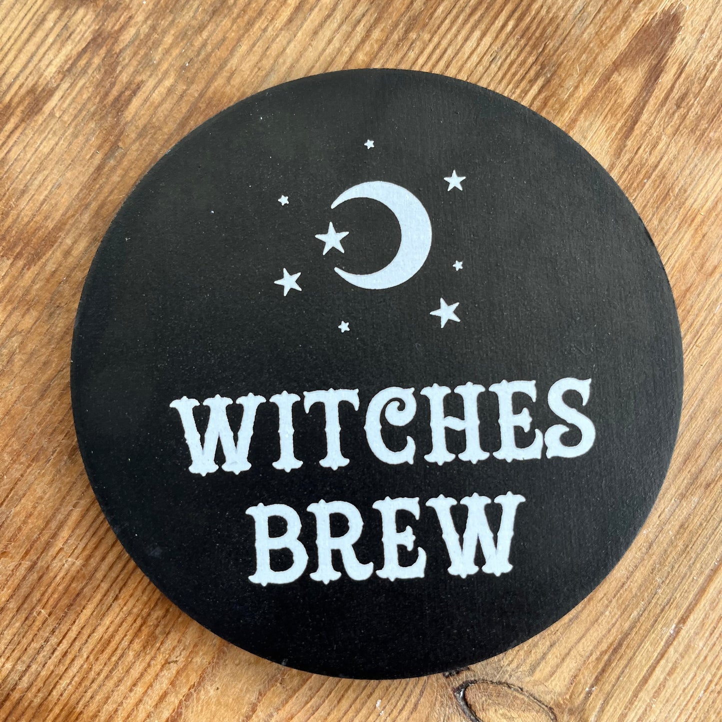 Black Coaster with the words 'witches brew' in white cursive text 