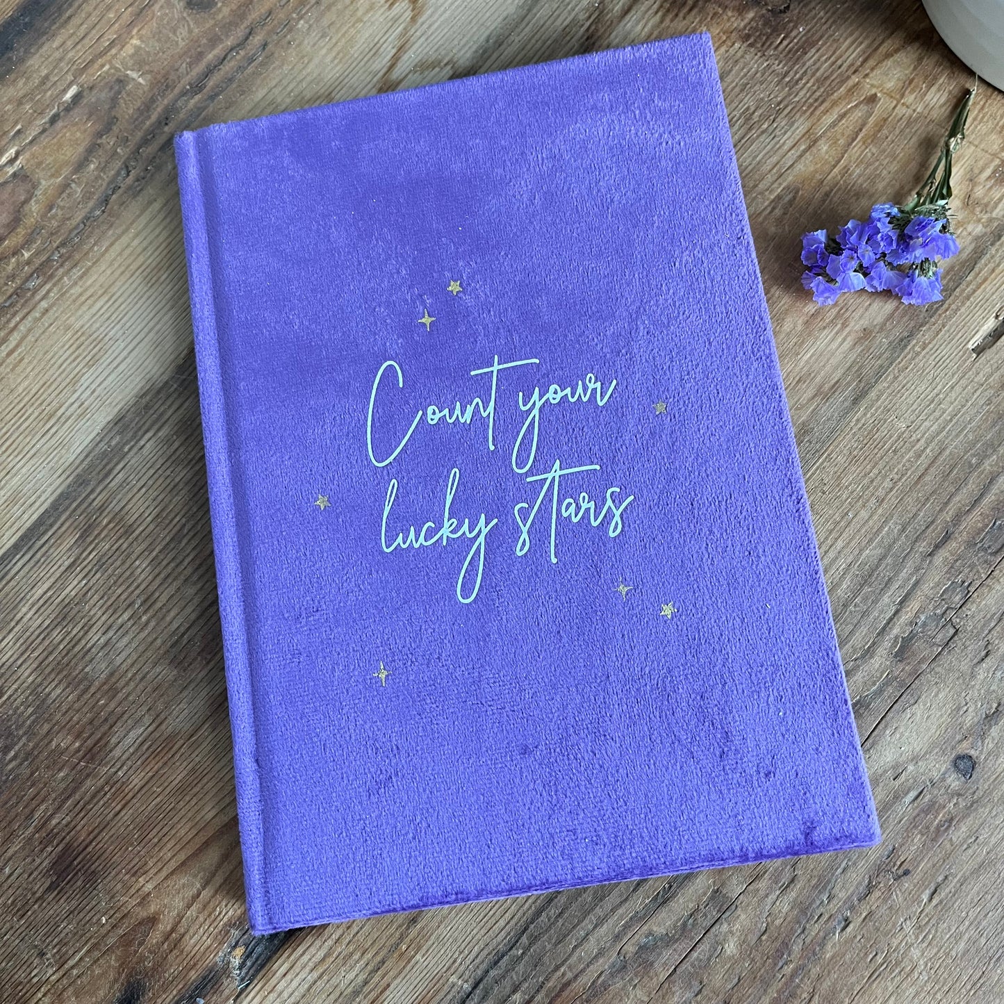 Purple velvet notebook with he words 'count your lcky stars' in script font 