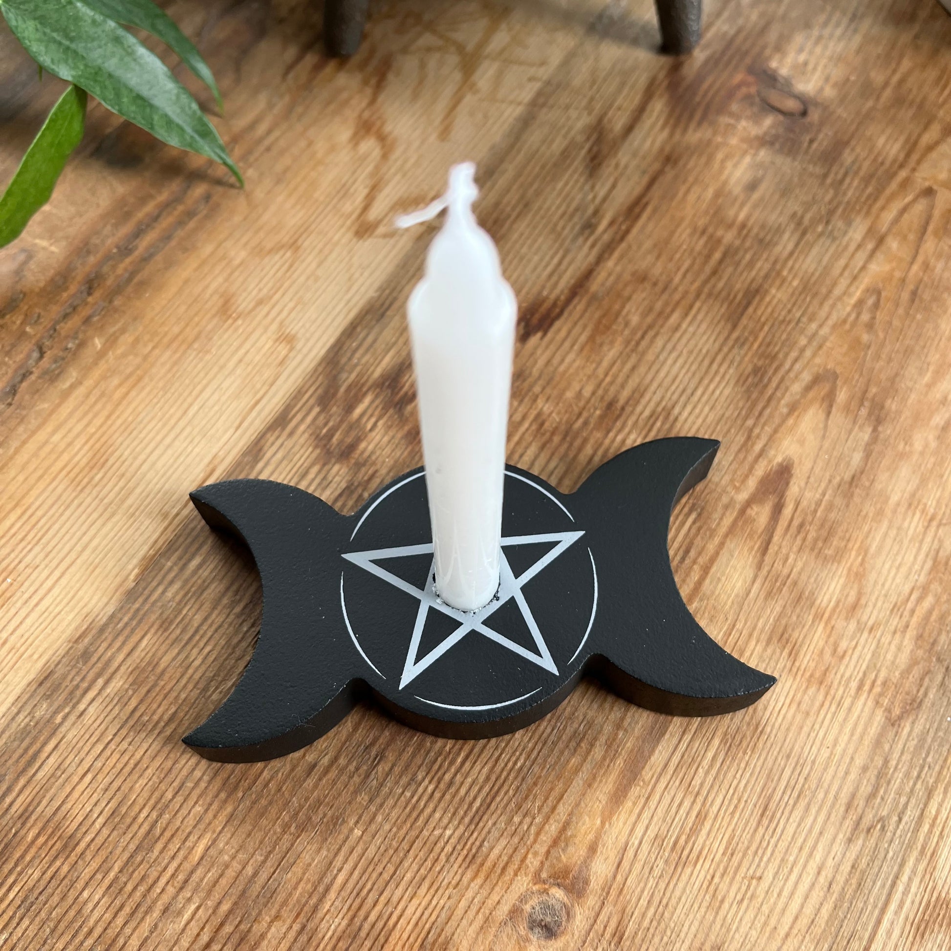 Black wooden spell candle holder in the shape of a triple moon with a Pentagram in white on its surface, holding a white spell candle