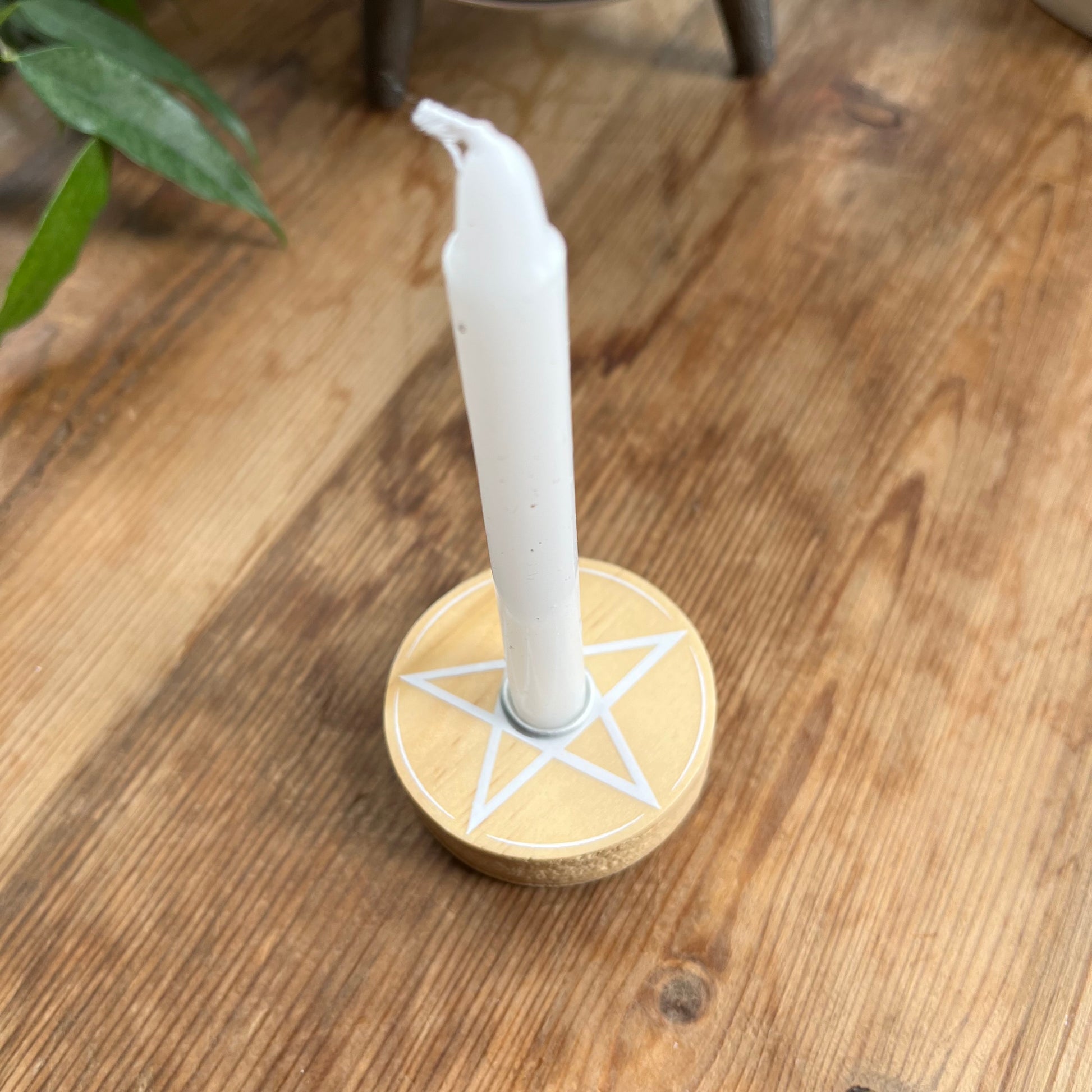 Natural wood circular spell candle holder with a white pentagram design on its surface 