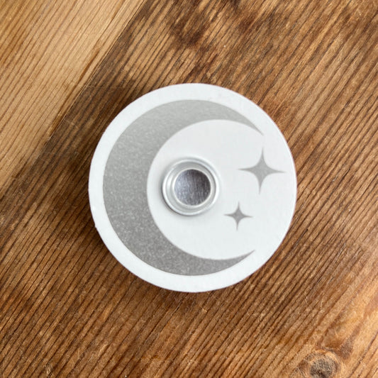 White circular wooden candle spell holder with a silver moon and star design on its surface 