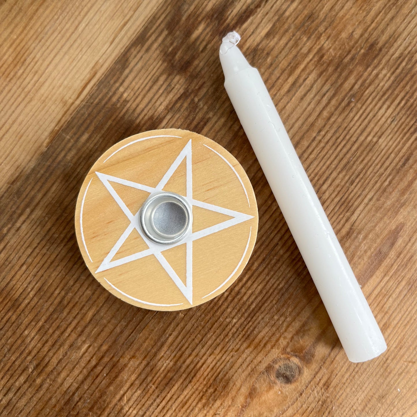 Natural wood circular spell candle holder with a white pentagram design on its surface 