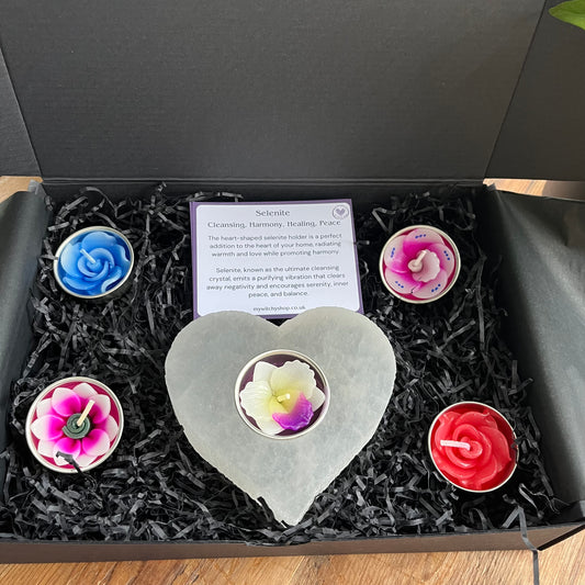 Chunky piece of natural selenite carved into a heart shape tealight holder. Alongside  collection of pretty coloured flower shaped tealights to use in the candle holder.  Presented in a black gift box. Also included are some cards explaining the metaphysical properties of selenite and colour associations. 