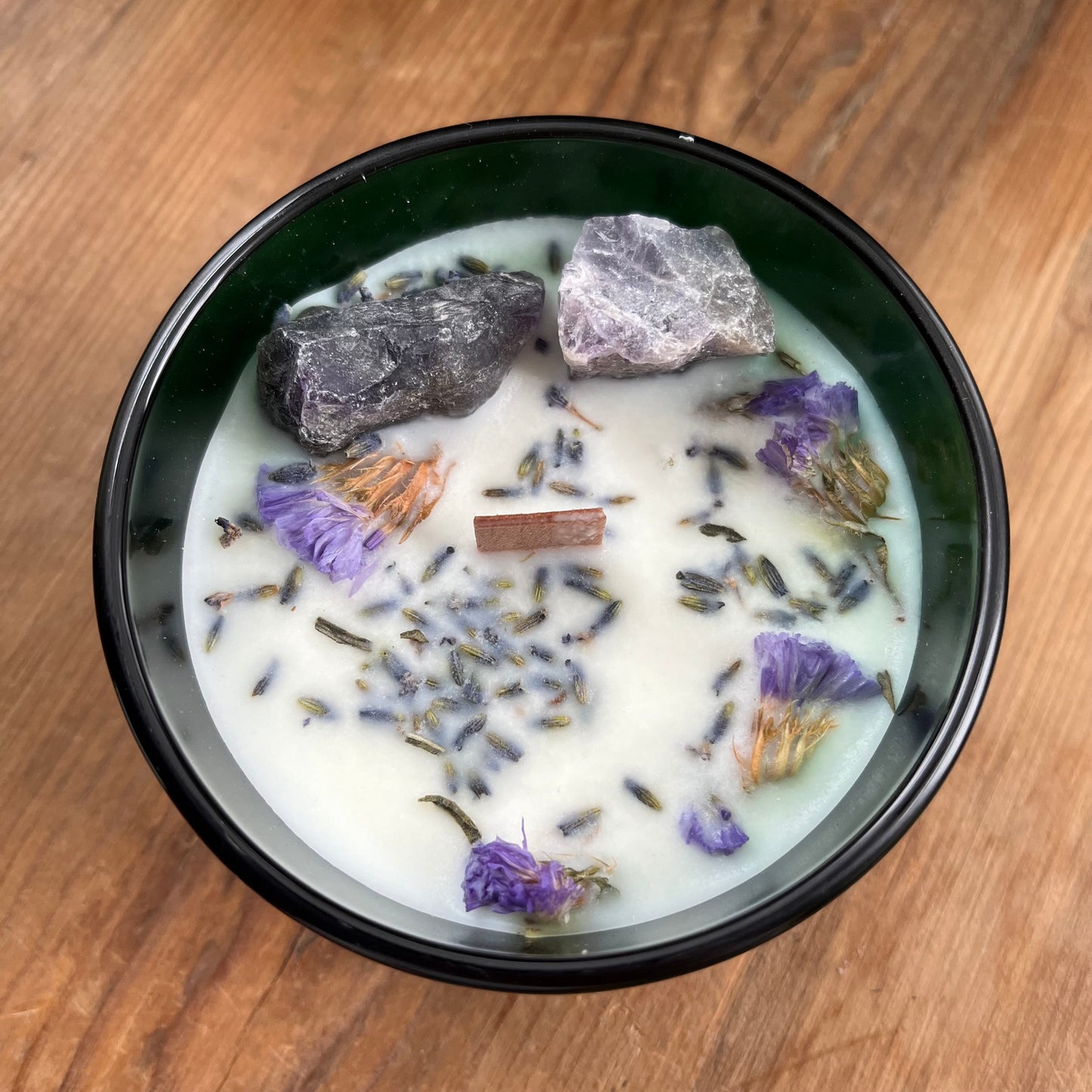 The top of the hop hare moon candle shows a wooden wick, large amethyst crystals and lavender flowers 