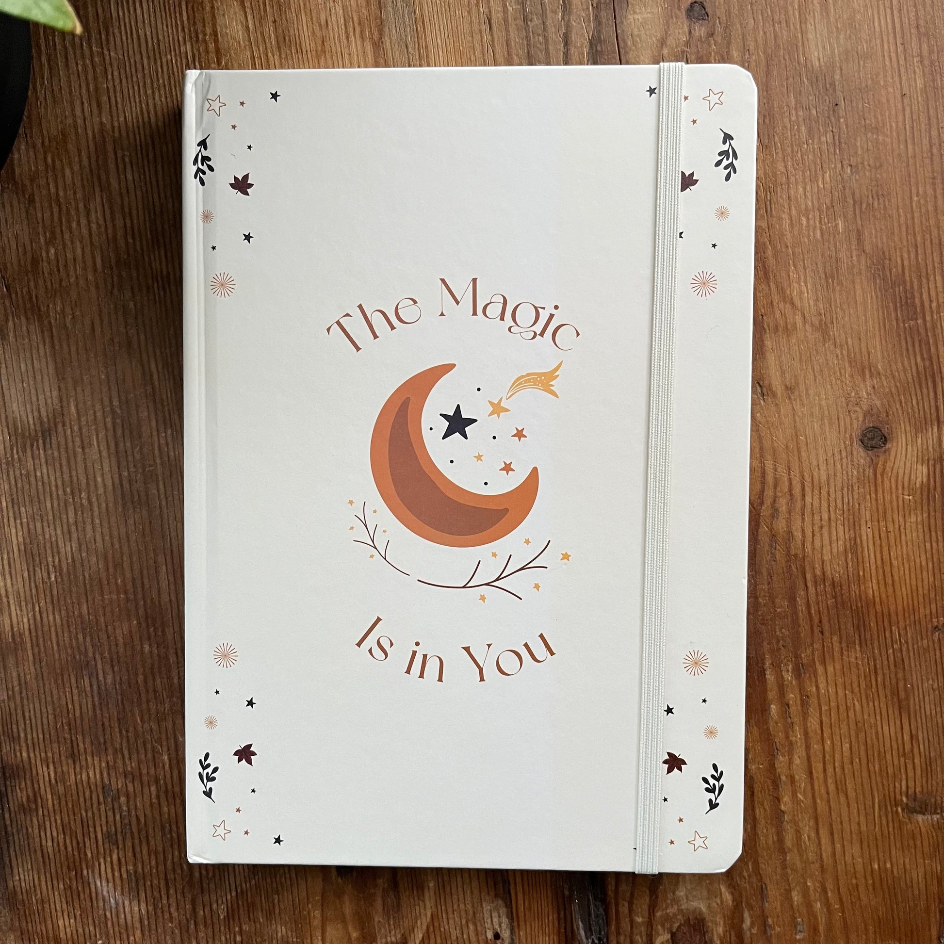 Notebook with 'The Magic is in You' design on a wooden surface