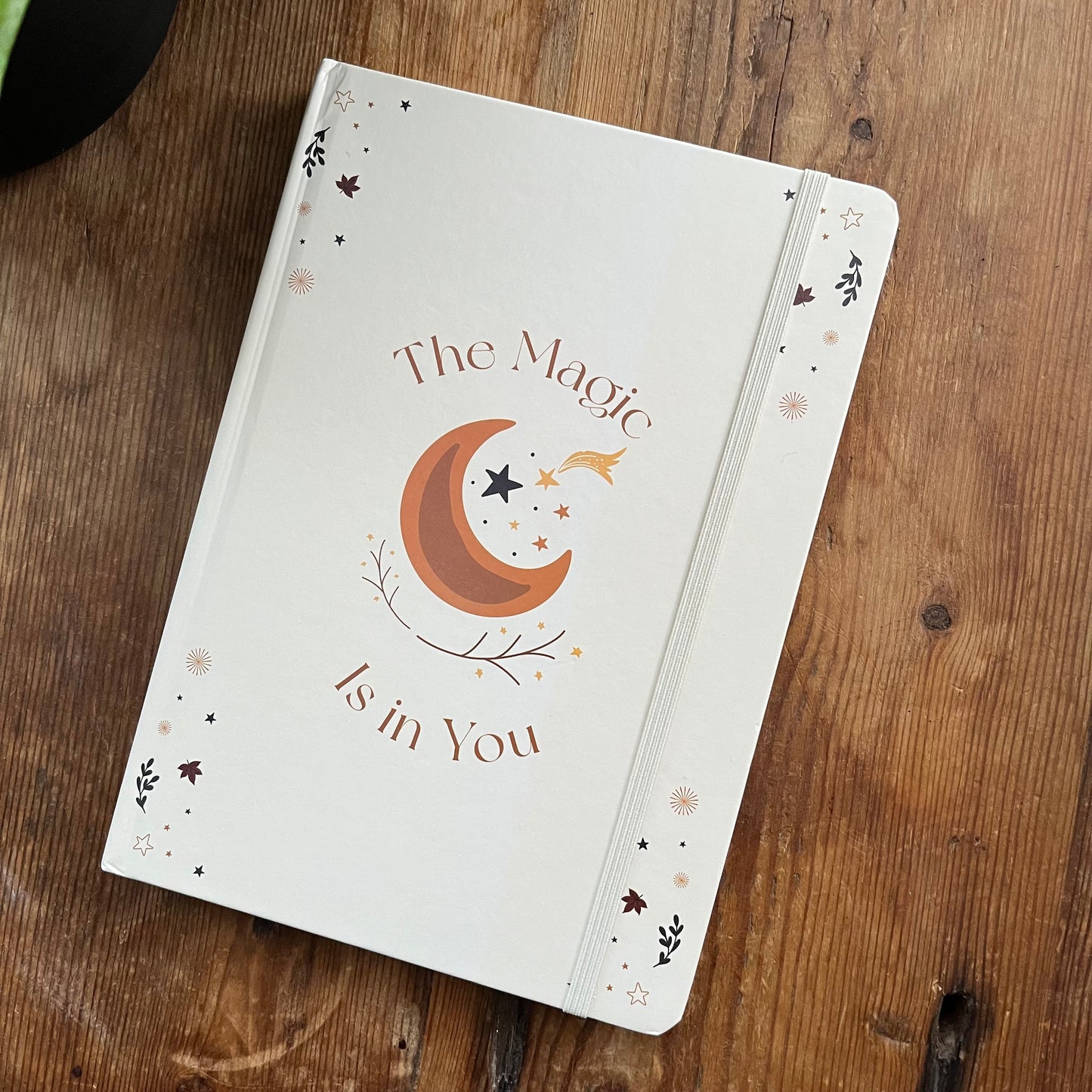 Notebook with 'The Magic is in You' design on a wooden surface