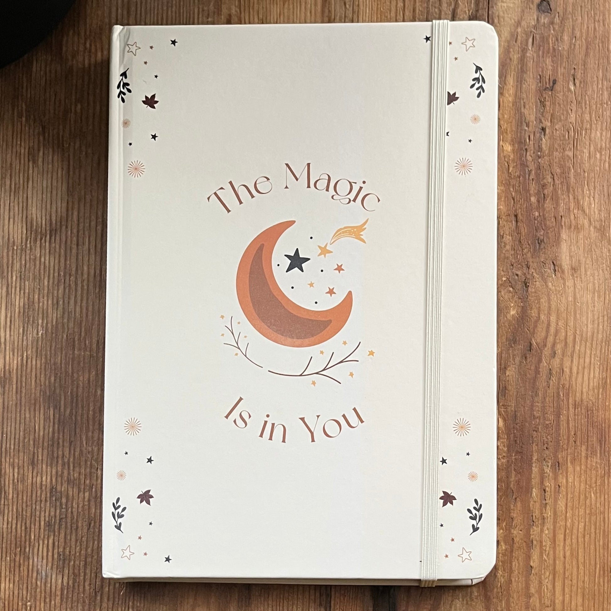 Notebook with 'The Magic is in You' design on a wooden surface