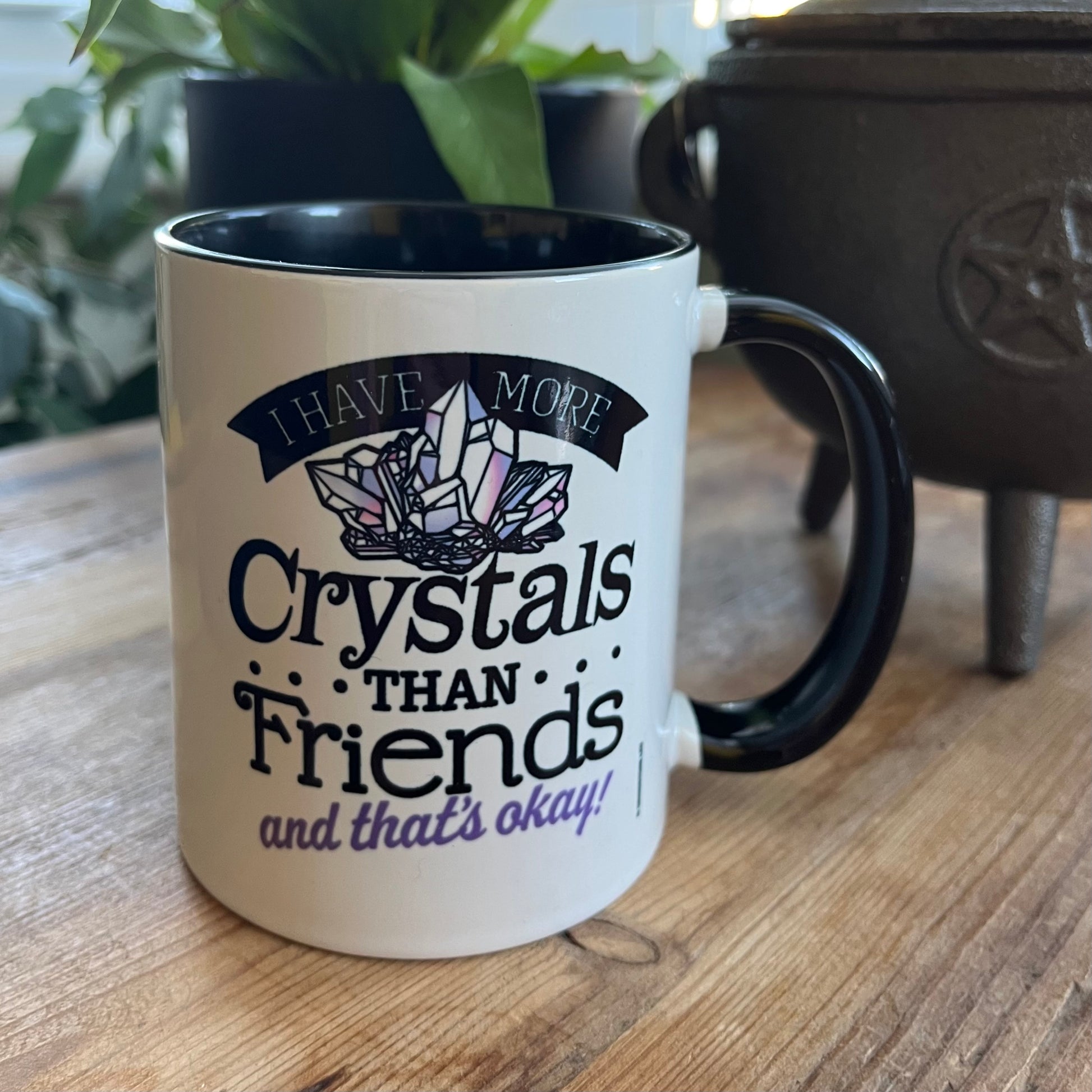 White mug with black interior and handle, featuring a crystal-themed design and text on a wooden surface.