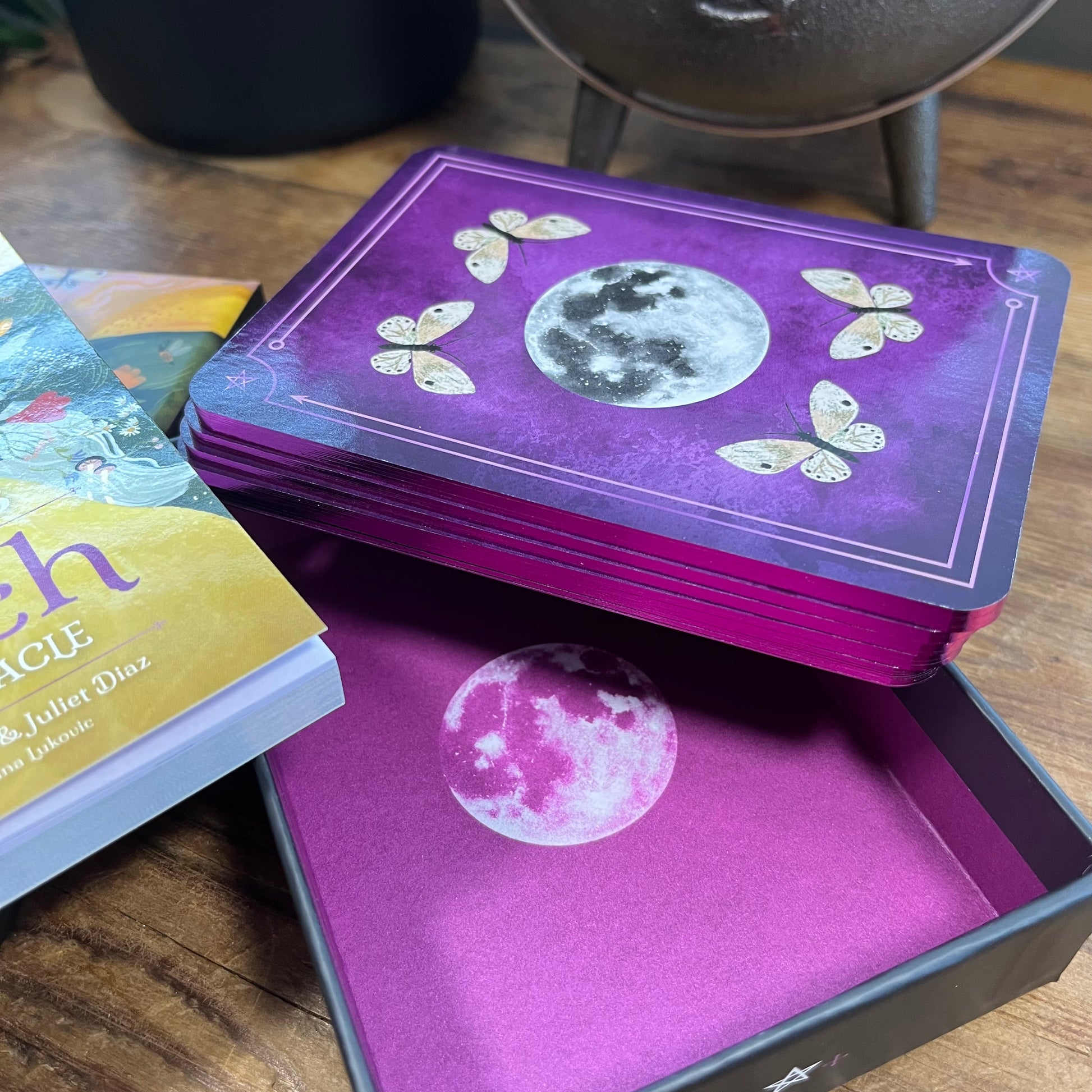 Purple tarot card deck with moon and butterfly design on a wooden surface