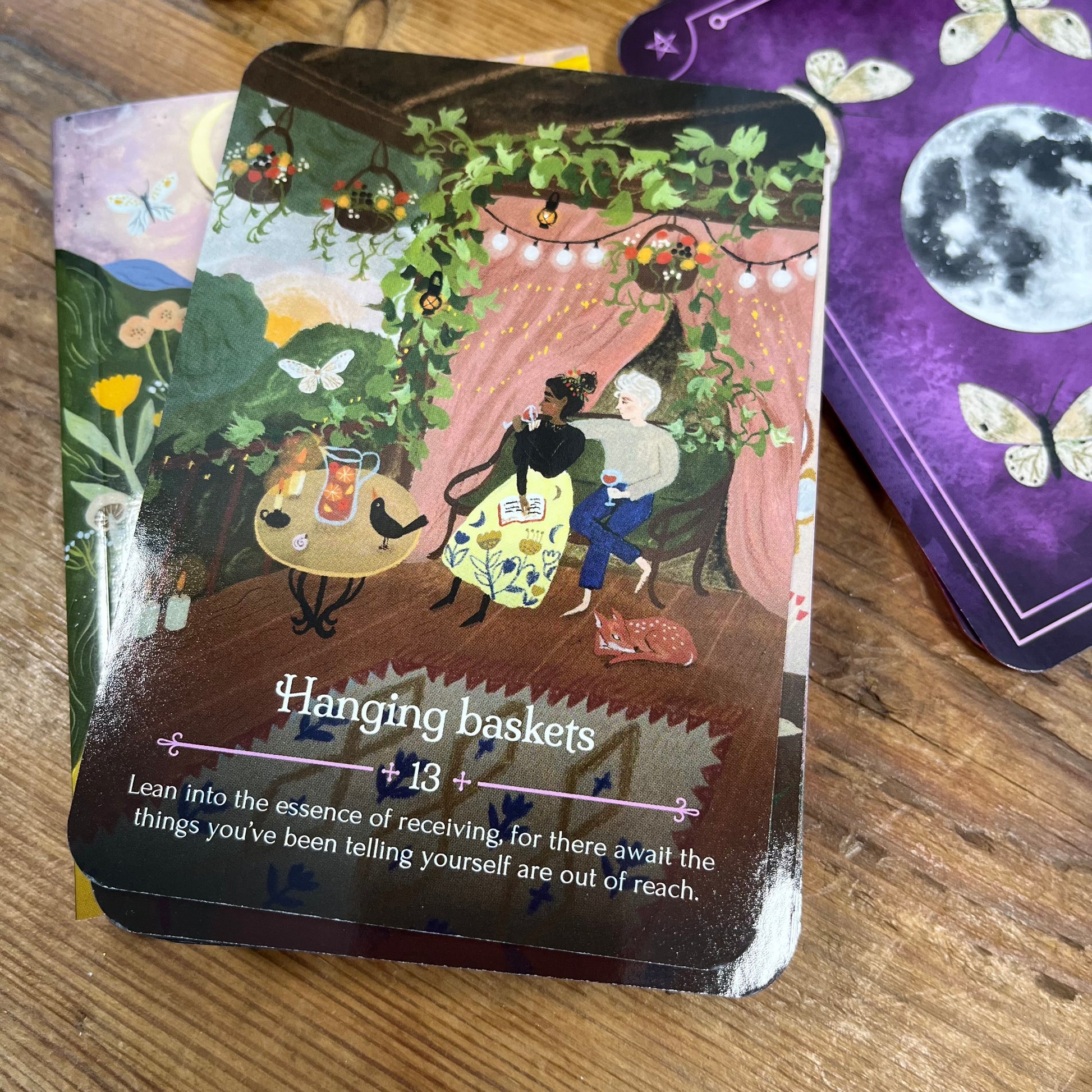 Oracle Card with an illustration of two people in a garden setting and text 'Hanging baskets 