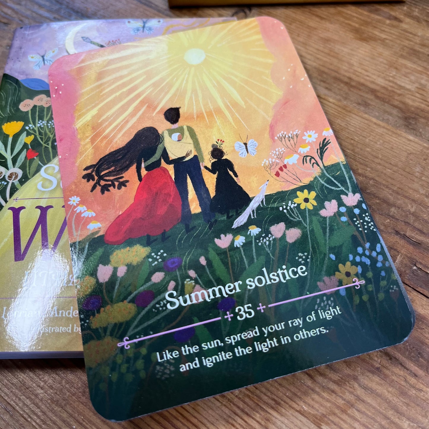 Oracle Card with an illustration of a couple and text 'Summer solstice on a wooden surface