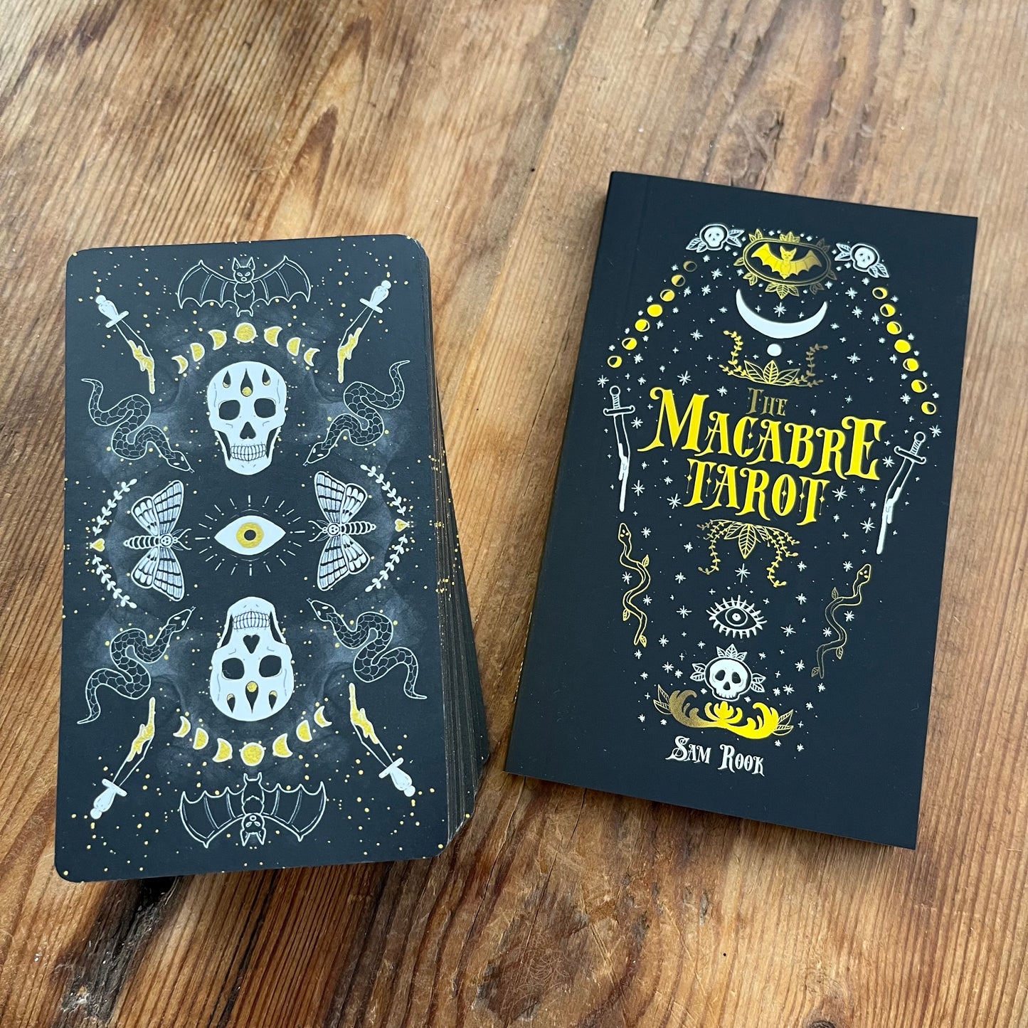 Two tarot card books with macabre designs on a wooden surface