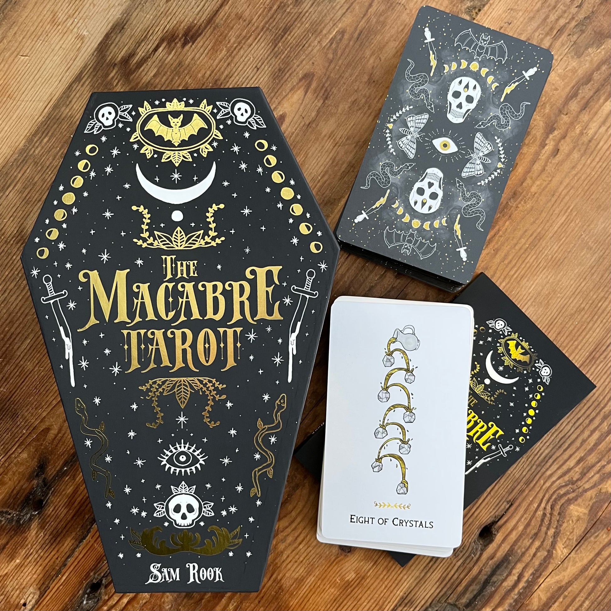 Macabre Tarot card set with coffin-shaped box on a wooden surface