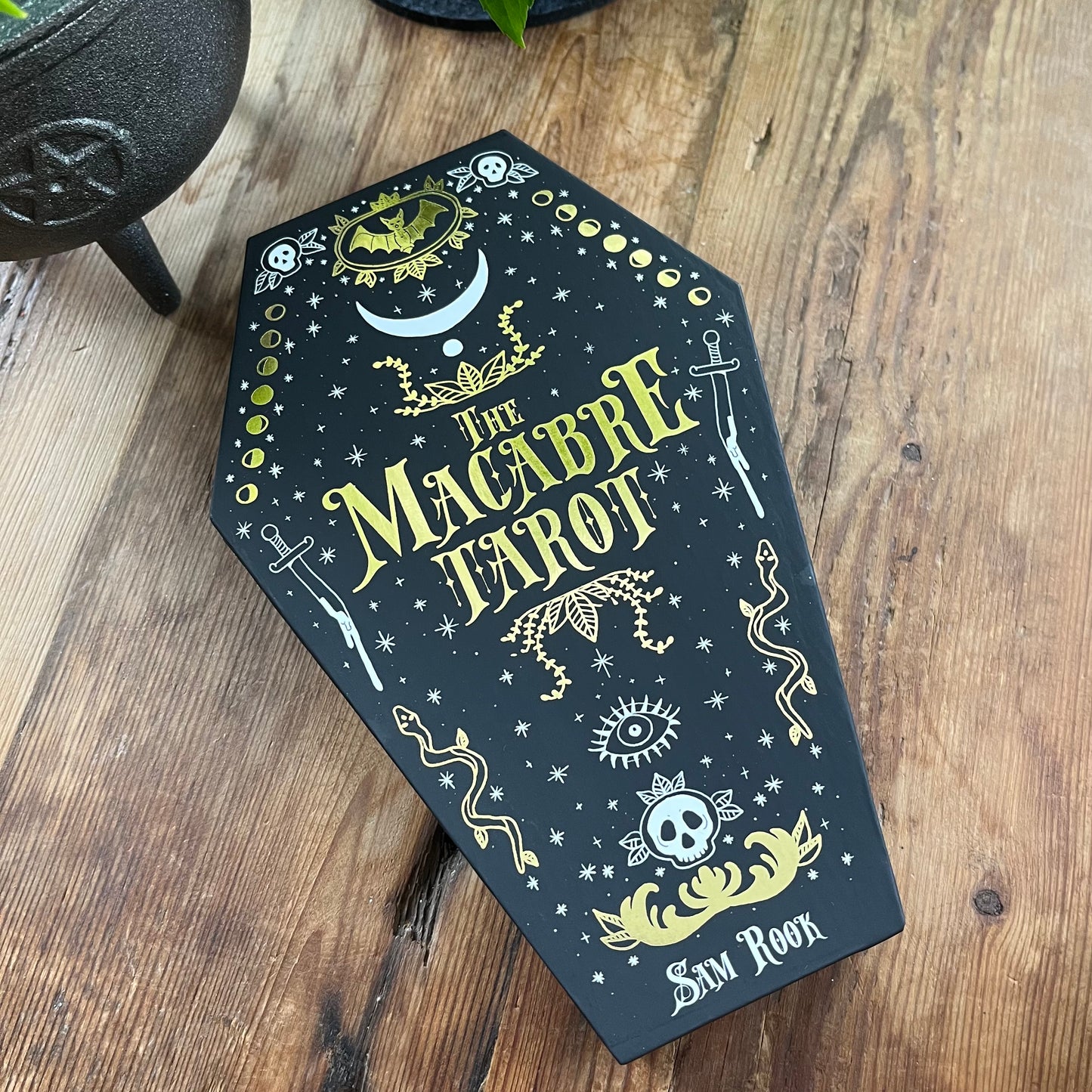 The Macabre Tarot on a wooden surface with a black cast iron cauldron.