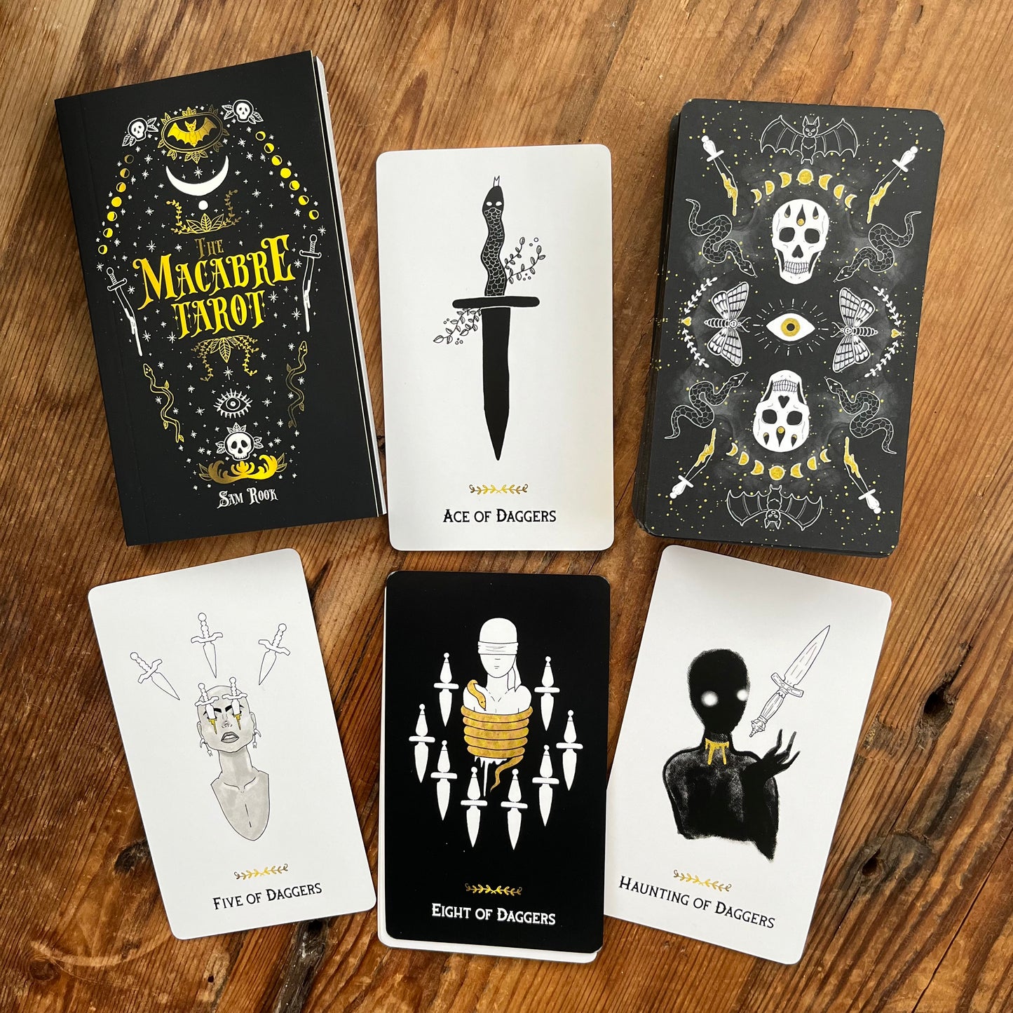 Collection of tarot cards with dark and white designs on a wooden surface