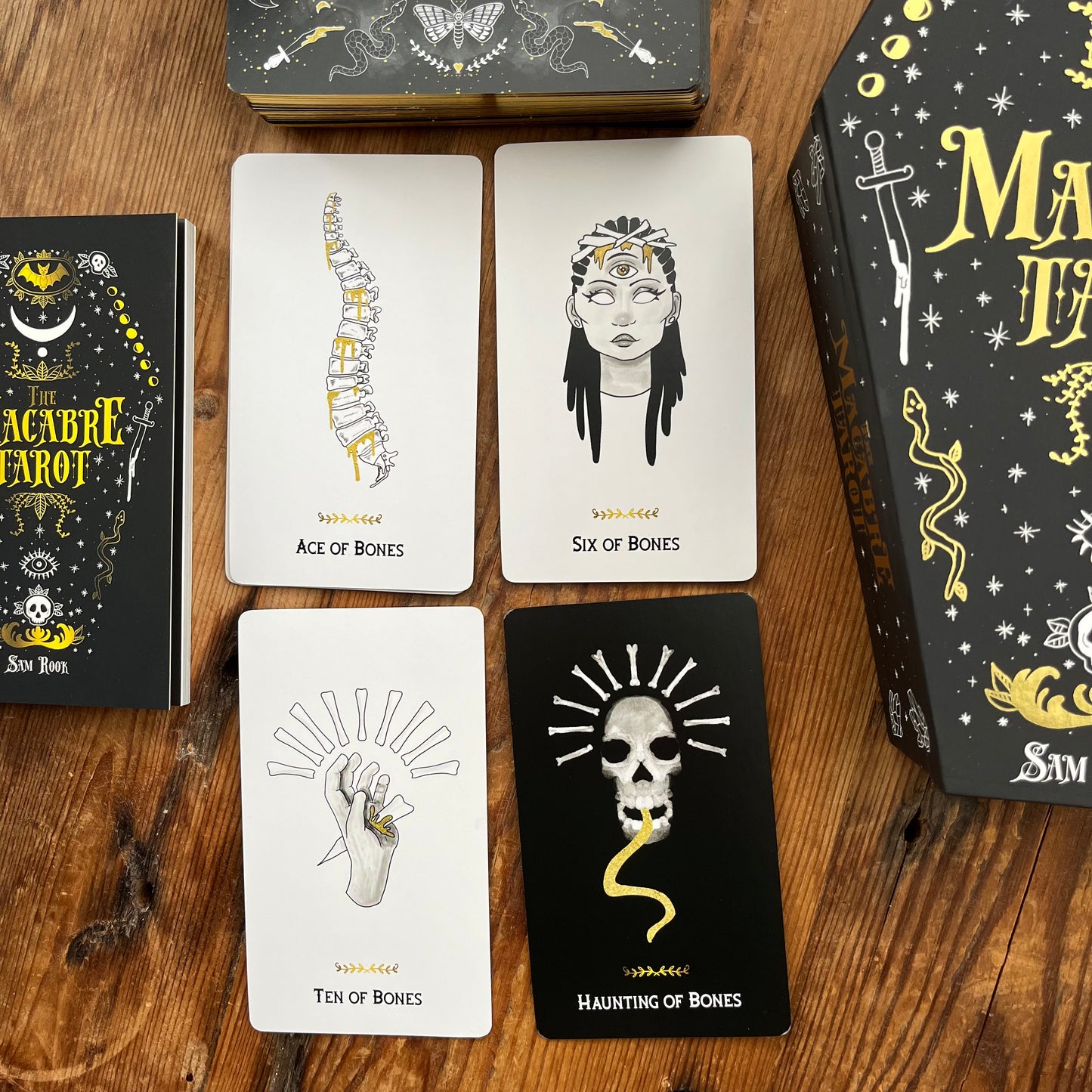 Collection of tarot cards on a wooden surface with 'The Macabre Tarot' box.