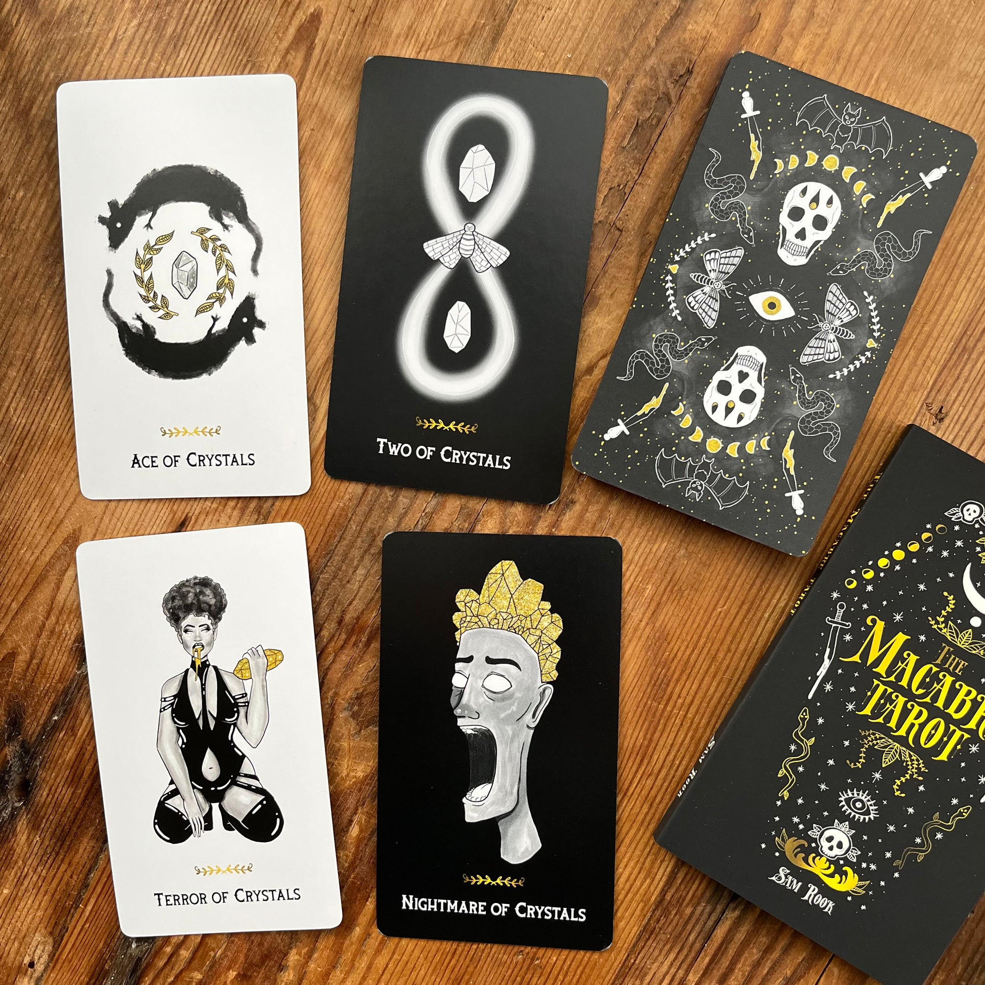 Collection of tarot cards with black and white illustrations on a wooden surface