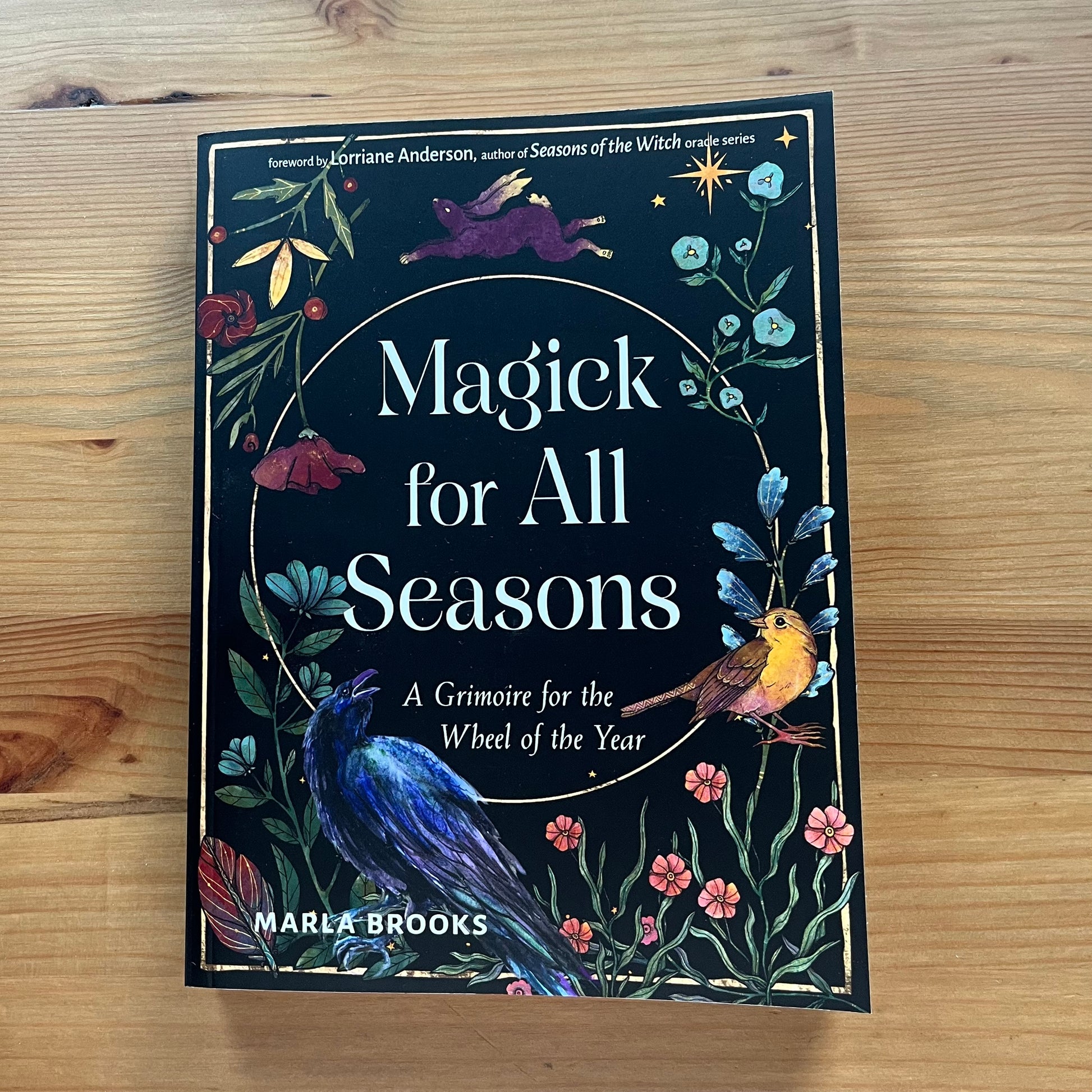 Book titled 'Magick for All Seasons' by Marla Brooks on a wooden surface