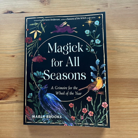 Book titled 'Magick for All Seasons' by Marla Brooks on a wooden surface