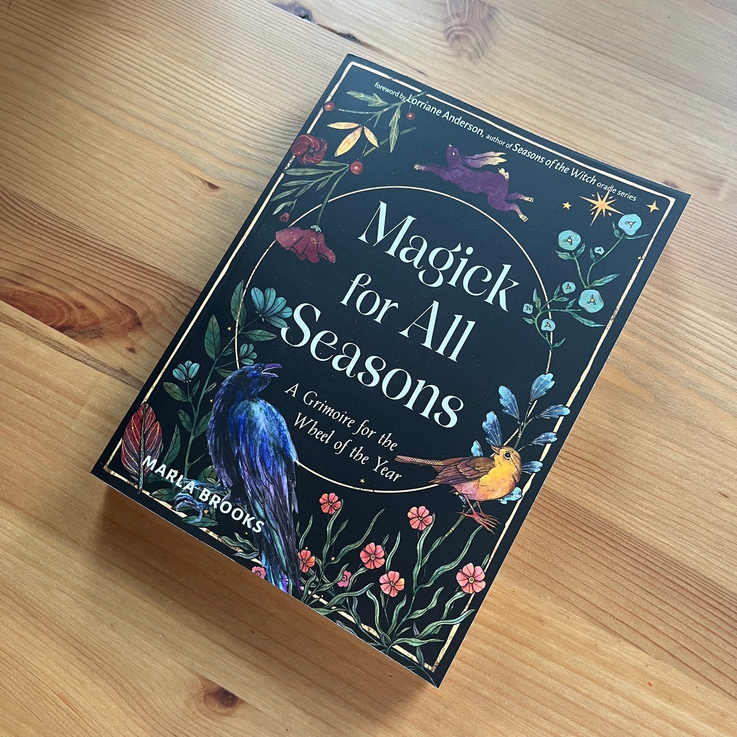 Book titled 'Magick for All Seasons' on a wooden surface