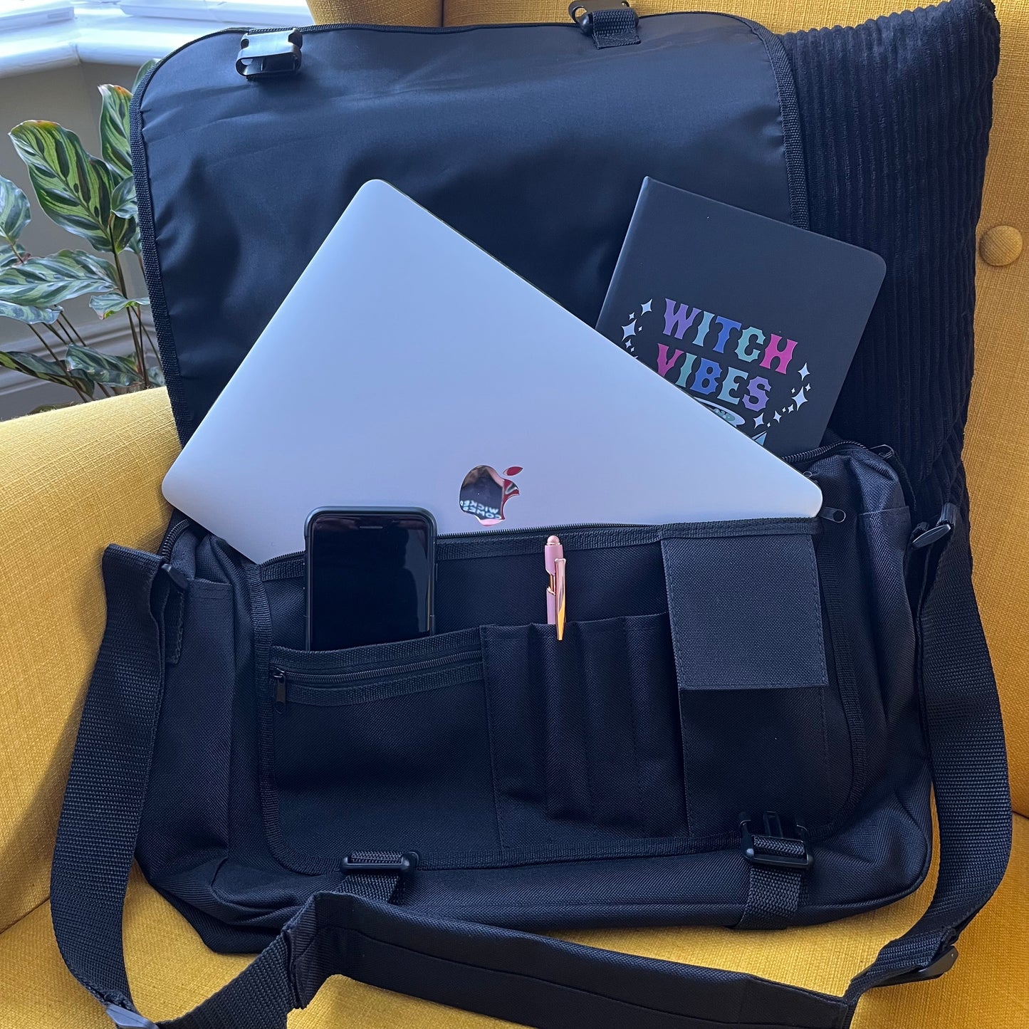 Black backpack with laptop, phone, and notebook on a yellow surface